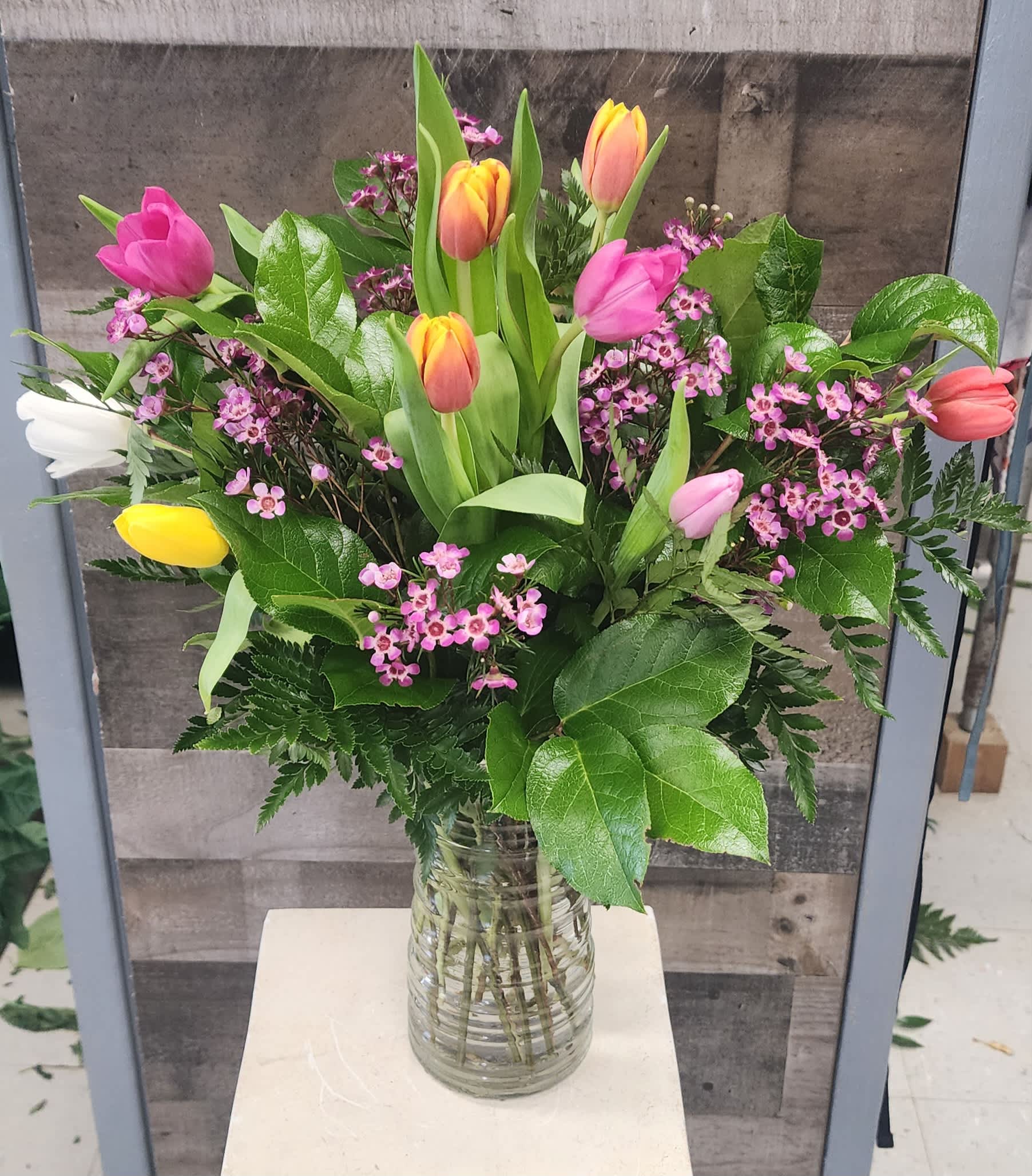 Mixed tulip bouquet with pink and yellow blooms in a glass vase
