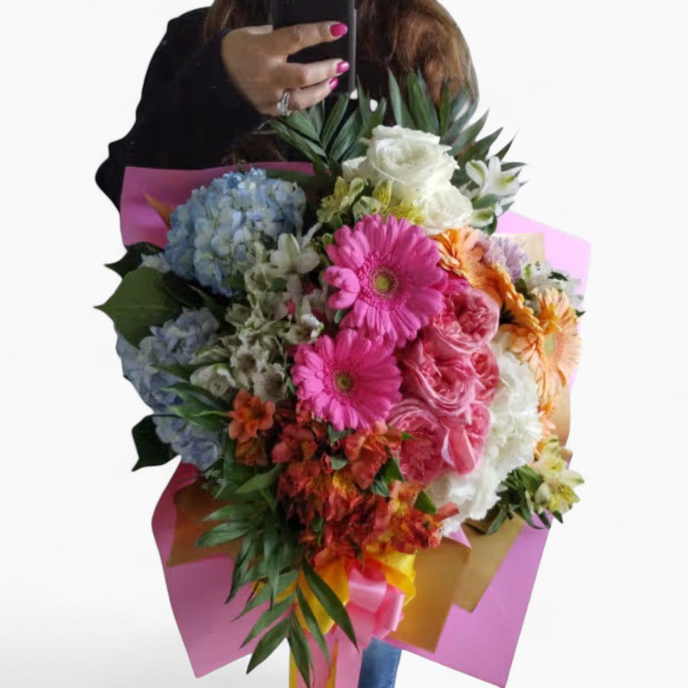 Large mixed bouquet of pink gerbera daisies, roses, hydrangeas and other flowers wrapped in pink and gold paper