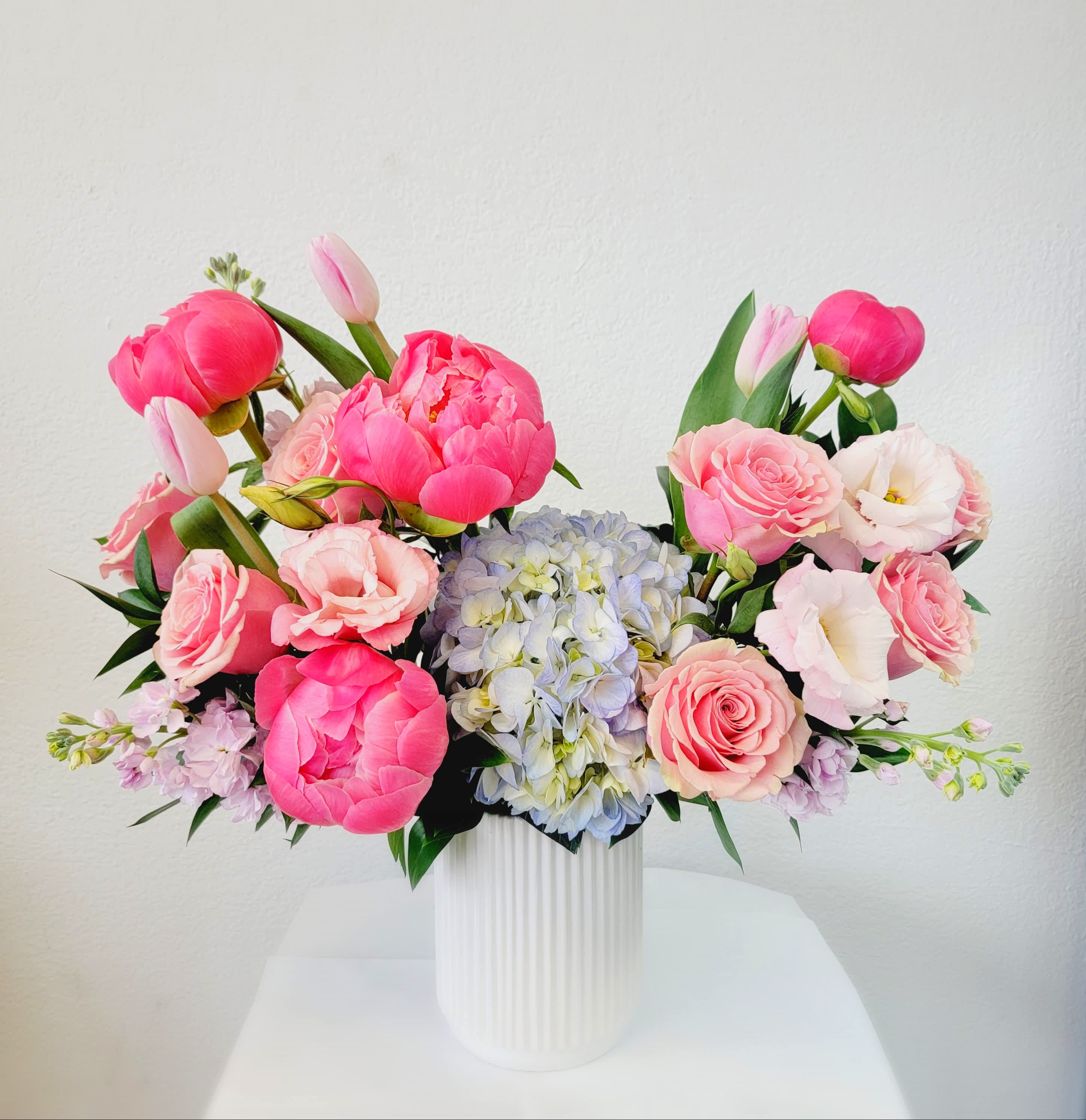 Pink and white floral arrangement in a white ribbed vase