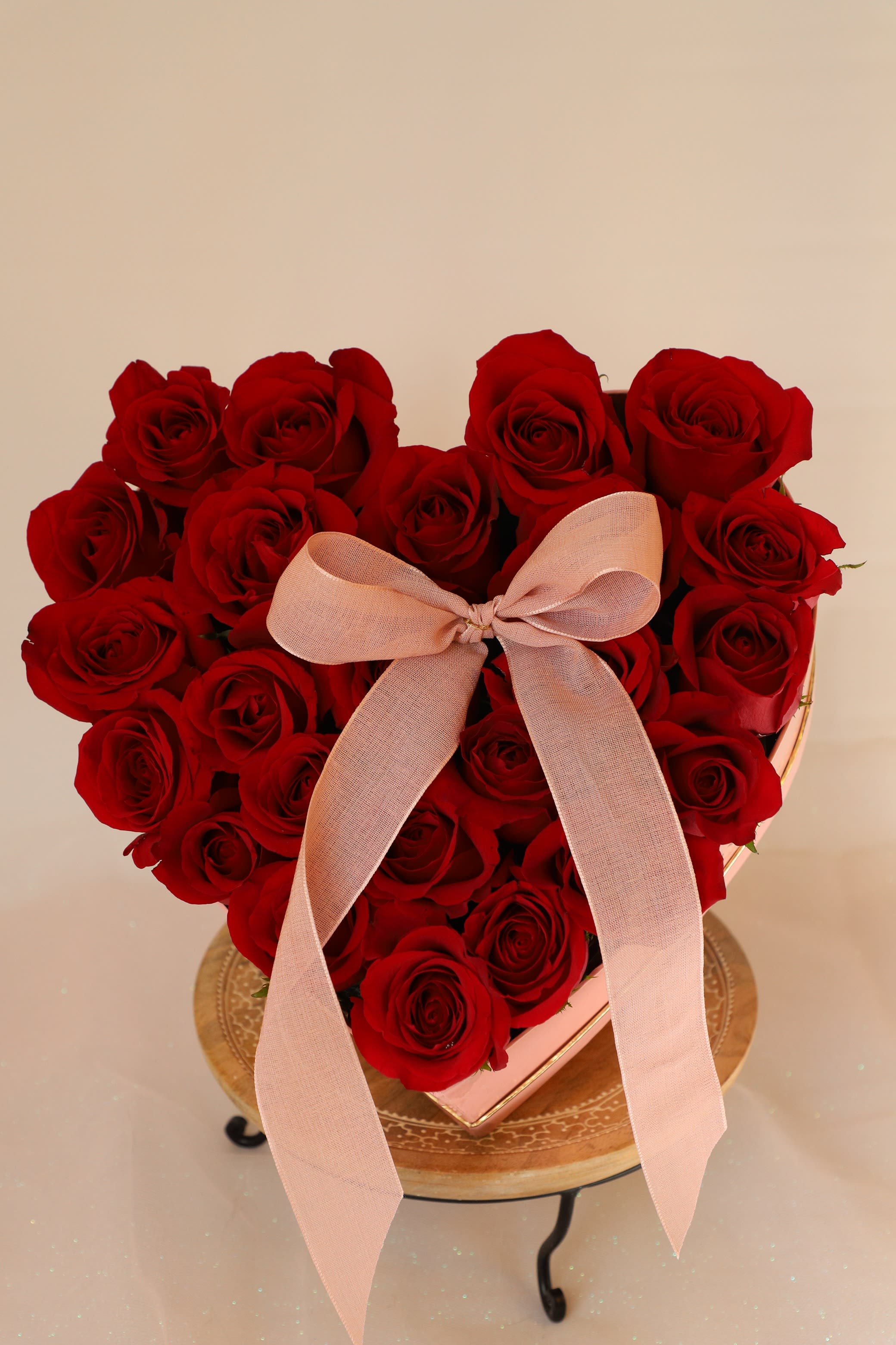 Heart-shaped box of red roses with a pink ribbon bow