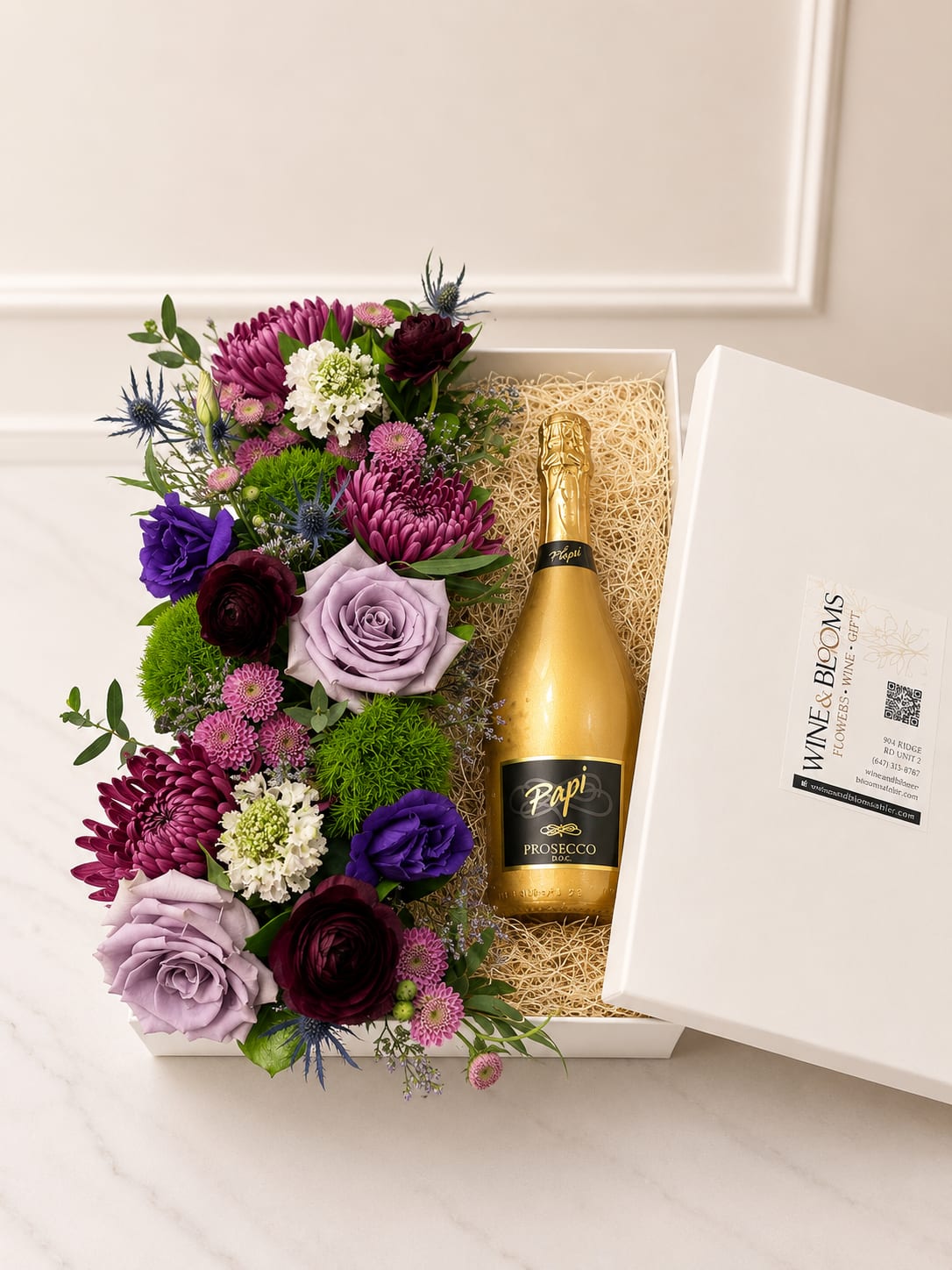 Lavender Luxe Floral &amp; Wine Collection | Prosecco  - Celebrate life's special moments with our Lavender Luxe Prosecco Gift Box, a sophisticated combination of premium blooms and sparkling indulgence. Perfect for anniversaries, congratulations, thank-you gifts, or simply making someone's day extra special.   Premium seasonal flowers  Bottle of Papi Gold Prosecco  Elegant keepsake gift box presentation  Designed fresh and uniquely by our floral designers  Flower varieties may vary based on seasonal availability while maintaining the overall color palette, style, and value of the design.   **To order wine from our catalog, both the customer and recipient must be at least 21 years old. Valid ID will be required upon delivery. By placing an order, you confirm that you and the recipient are of legal drinking age.