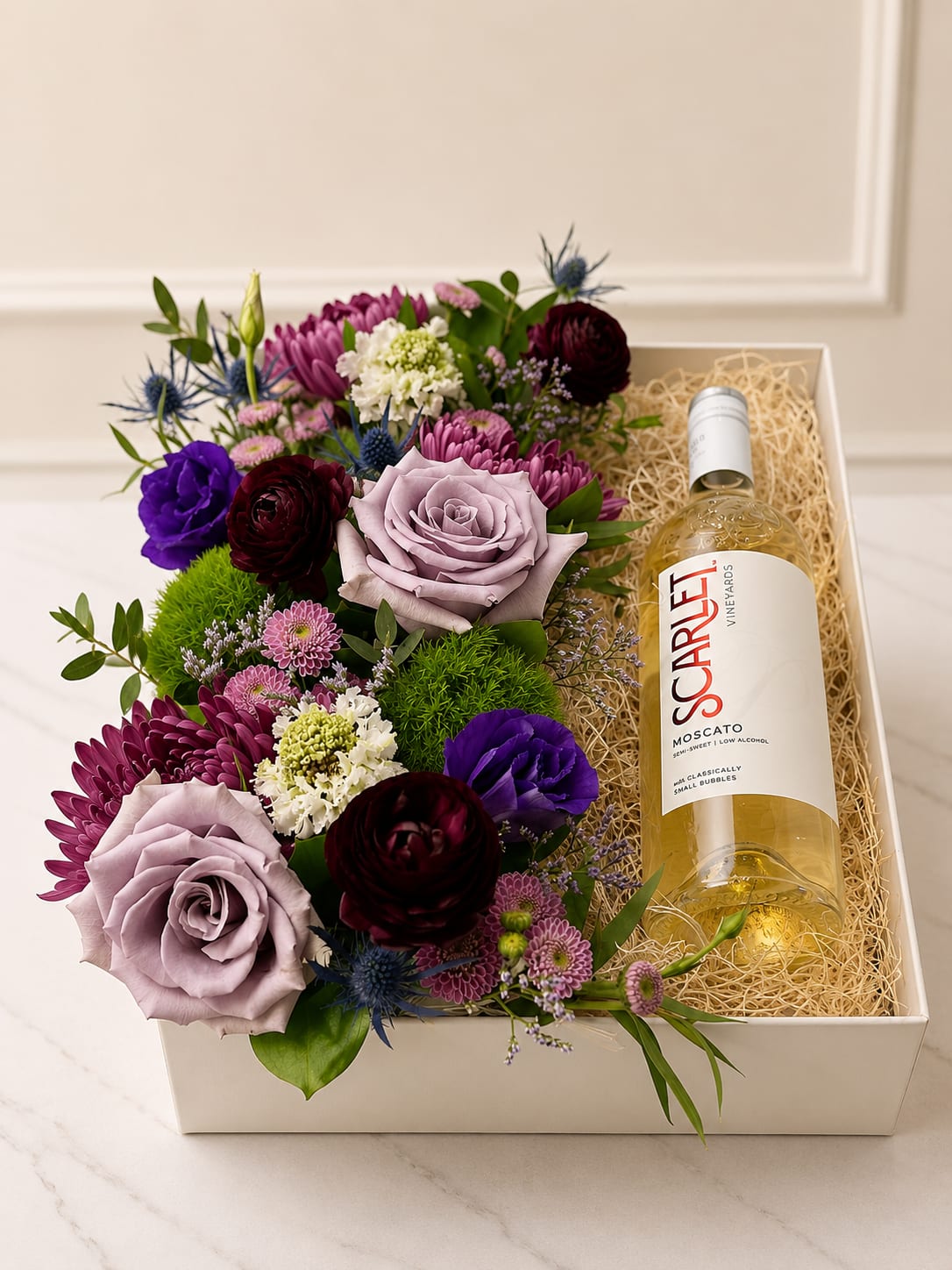 Lavender Luxe Floral &amp; Wine Collection | Moscato - Celebrate life's special moments with our Lavender Luxe Moscato Gift Box, a sophisticated combination of premium blooms and sweet sparkling indulgence. Featuring a bottle of Scarlet Vineyards Moscato paired with an elegant arrangement of seasonal flowers in soft lavender, rich plum, and vibrant jewel tones, this gift is designed to leave a lasting impression.  Perfect for anniversaries, congratulations, thank-you gifts, or simply making someone's day extra special.   Premium seasonal flowers  Bottle of Scarlet Vineyards Moscato  Elegant keepsake gift box presentation  Designed fresh and uniquely by our floral designers  **To order wine from our catalog, both the customer and recipient must be at least 21 years old. Valid ID will be required upon delivery. By placing an order, you confirm that you and the recipient are of legal drinking age.