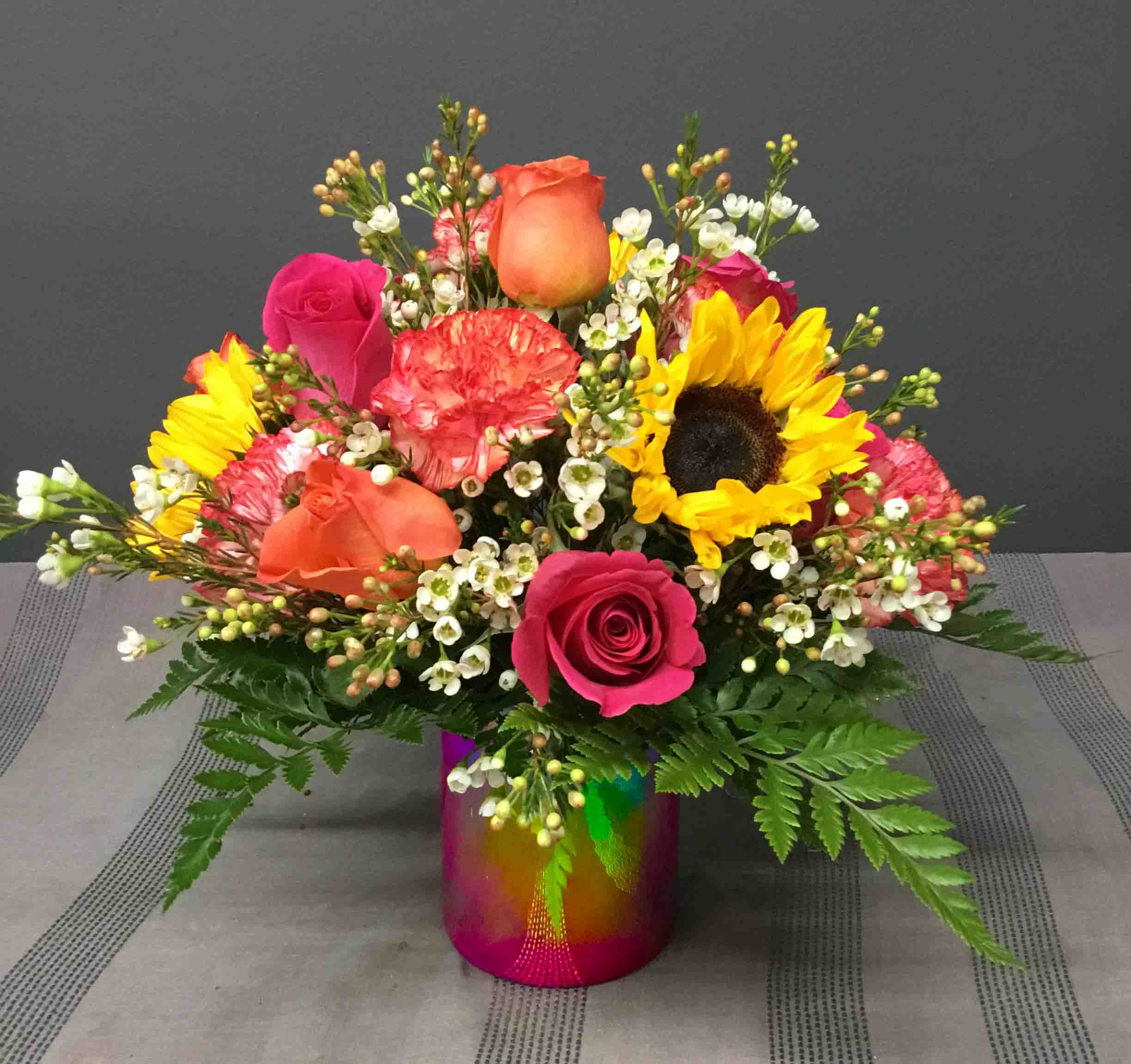 Hot Stuff - Sunflowers, Carnations and assorted brights in a Hot Pink Metalic Vase