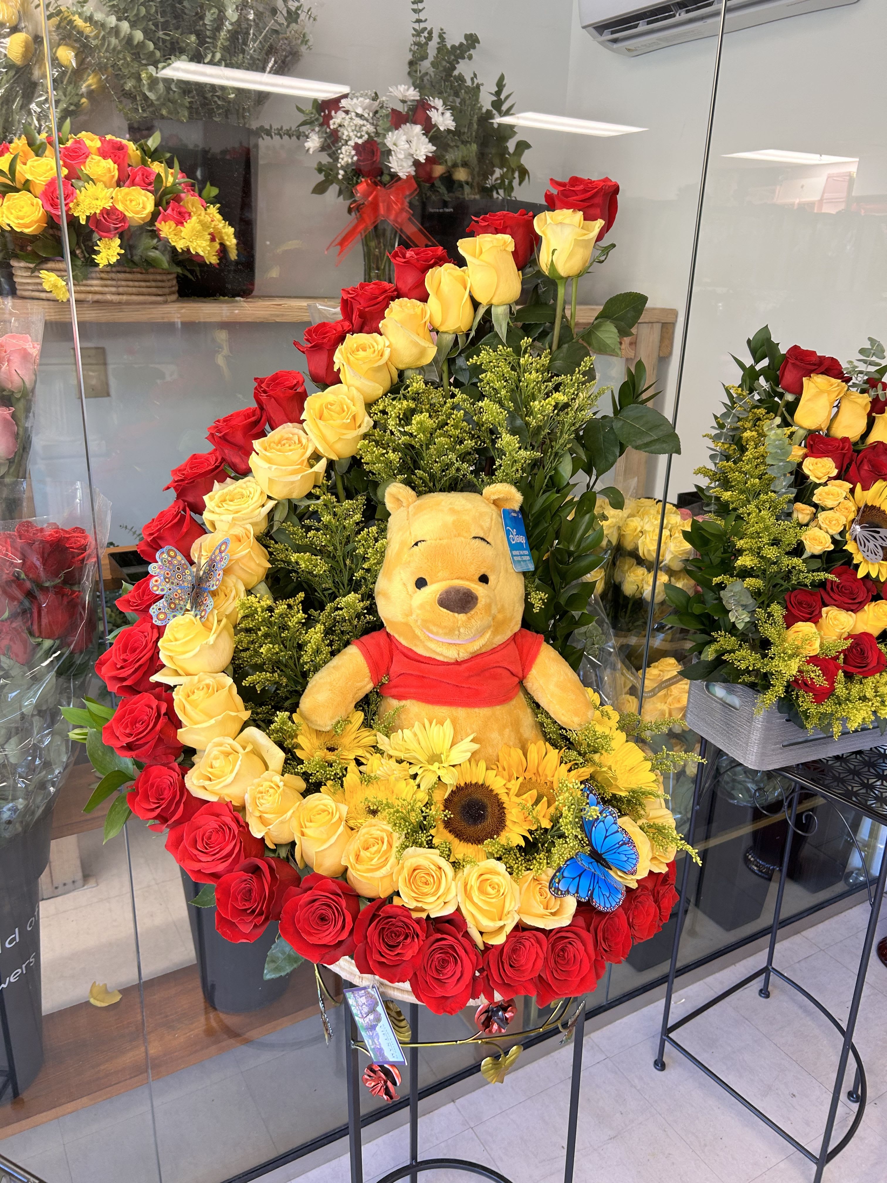 Large rose arrangement with a Winnie the Pooh plush and yellow flowers