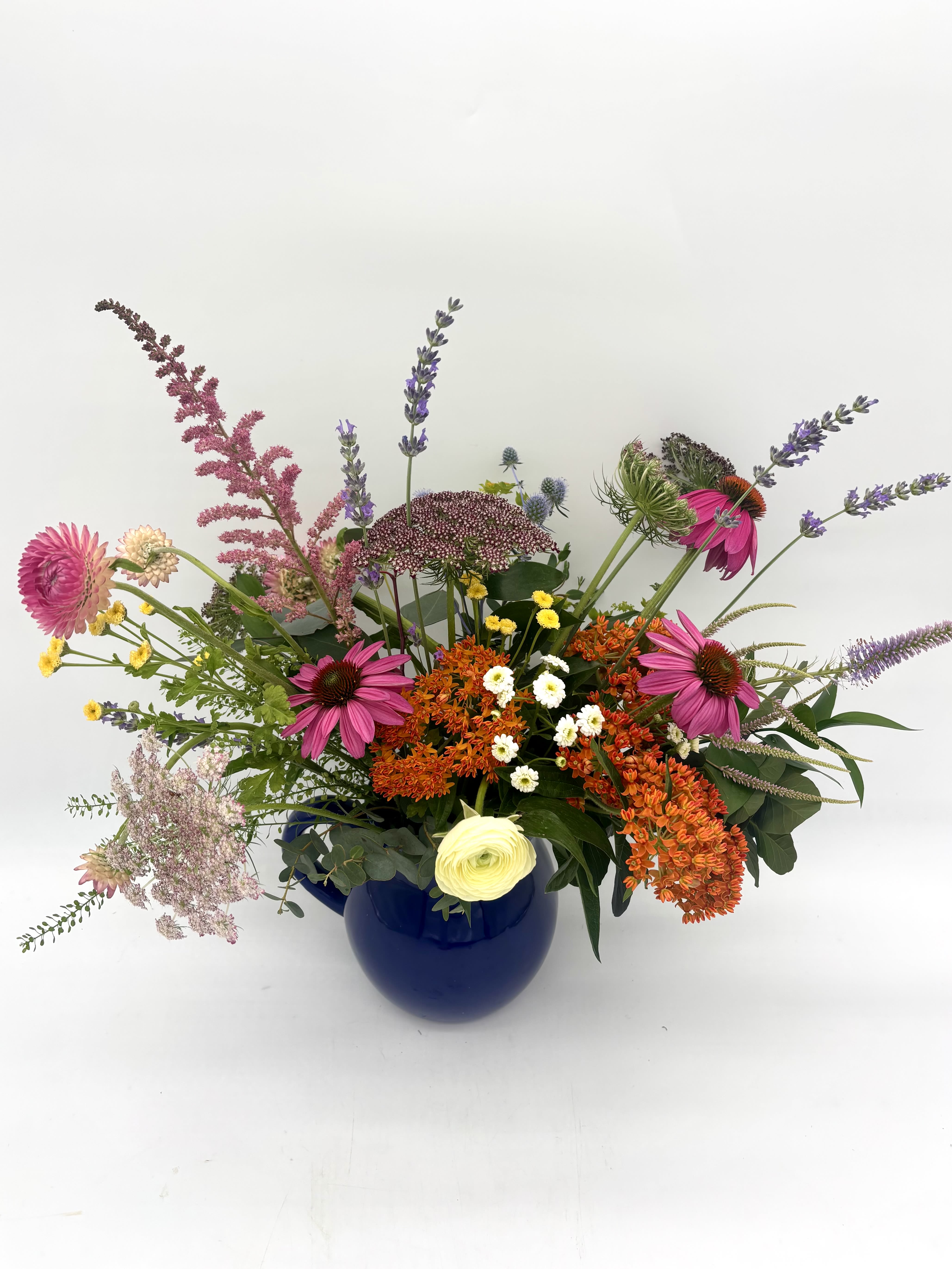 Pitcher Perfect - Fresh-picked summer charm in a pitcher! This vibrant arrangement features a colorful mix of seasonal summer blooms, sourced from local farms, and is beautifully designed in a reusable ceramic pitcher that's perfect for all your summer events. Flower varieties and colors may vary, and similar substitutions may be made based on seasonal availability while maintaining the overall style, color palette, and value of the arrangement.