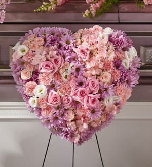 Heart-shaped floral arrangement of pink, lavender, and white blooms on an easel