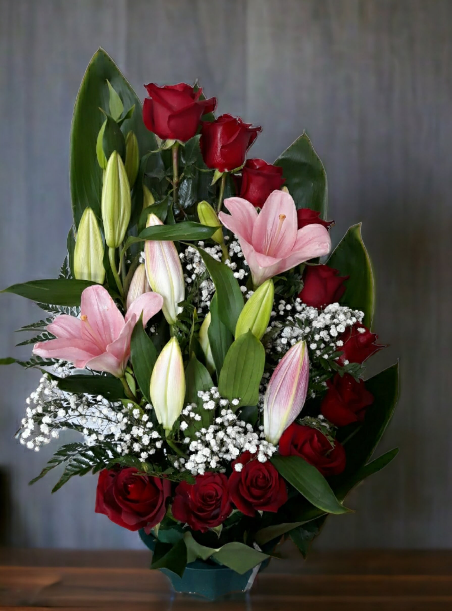 Red roses and pink lilies in a vase with baby's breath