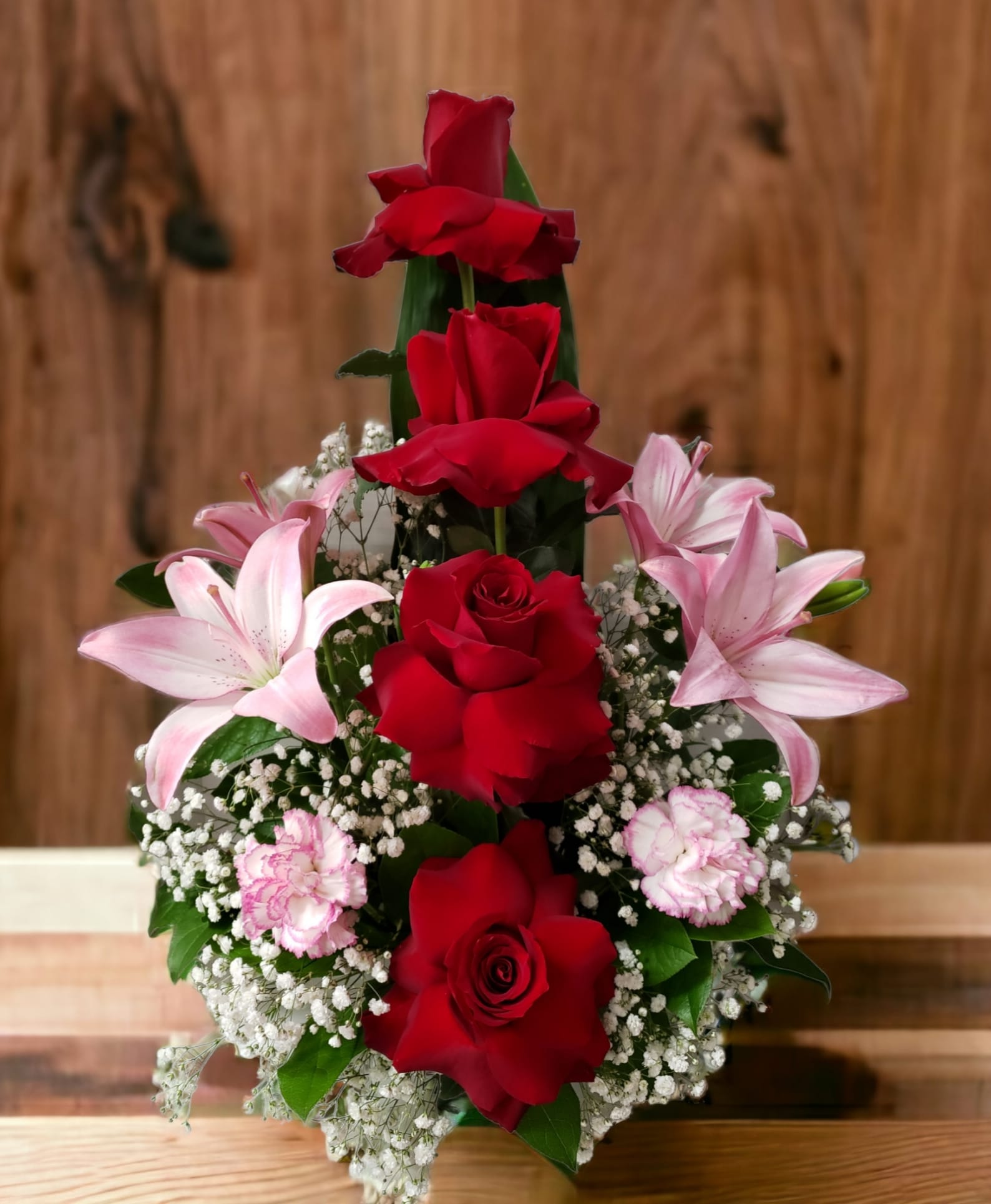 Red roses with pink lilies and carnations in a tiered arrangement