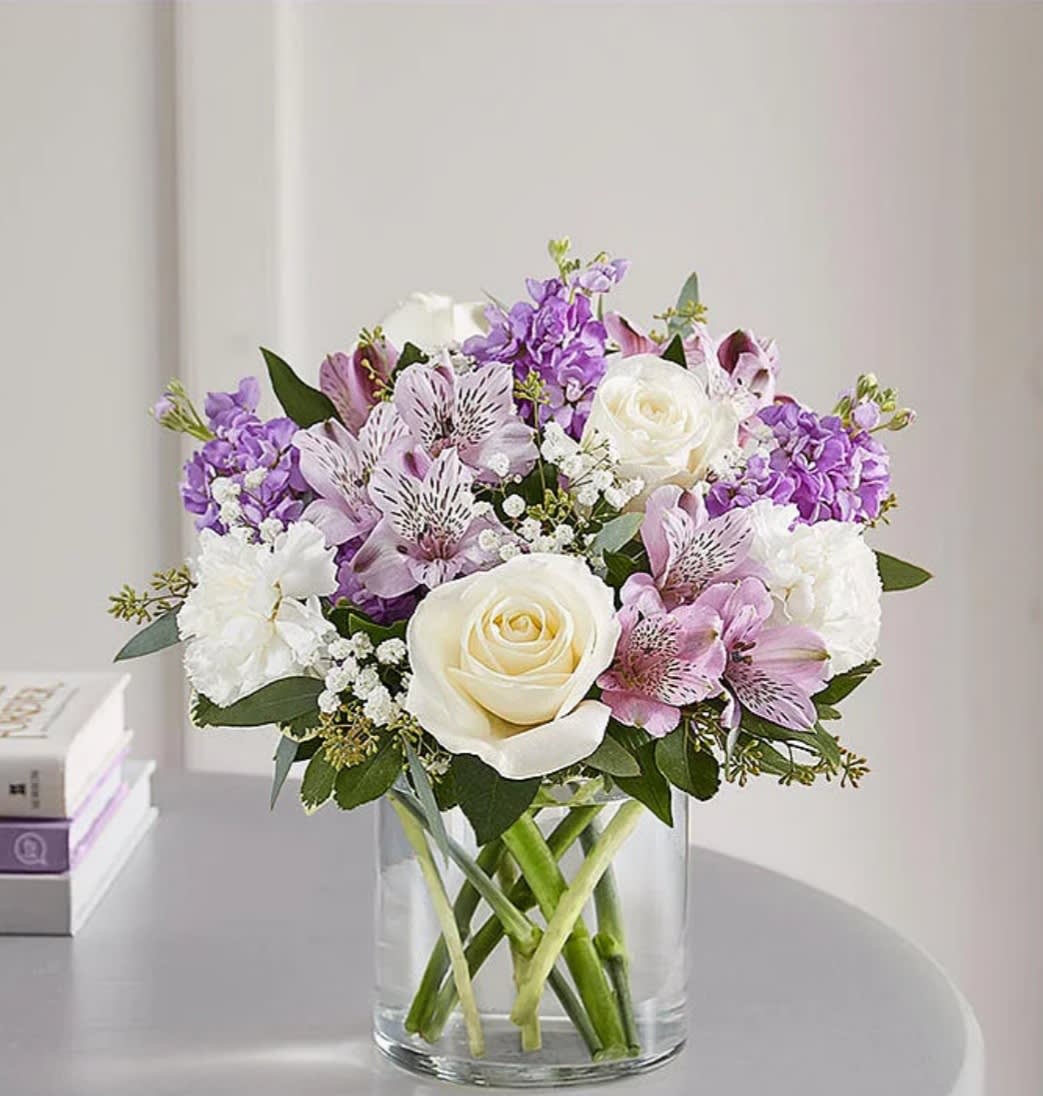Bouquet of white roses, purple flowers, and pink lilies in a glass vase