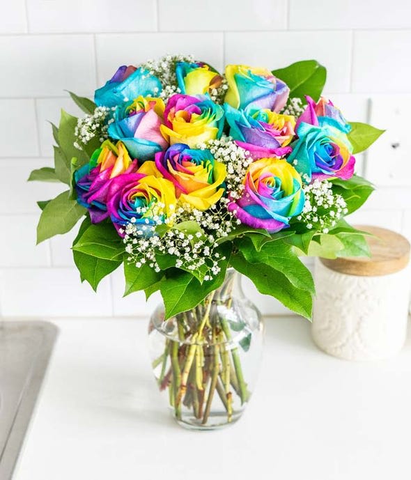 Bouquet of rainbow-colored roses in a clear glass vase