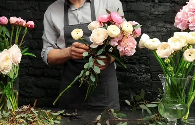 Florist holding a bouquet of pale pink and cream ranunculus