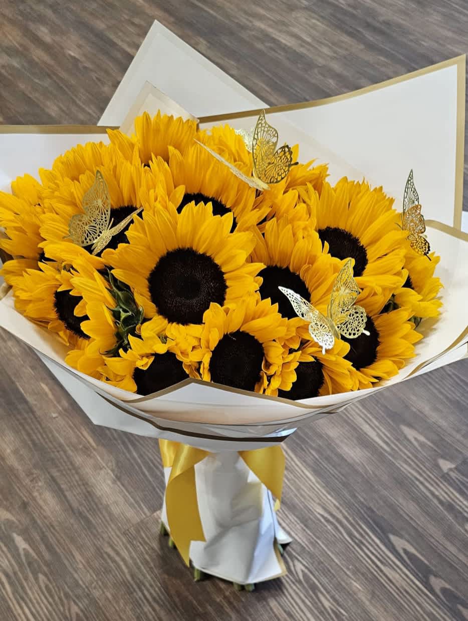 Bouquet of yellow sunflowers wrapped in white paper with gold trim