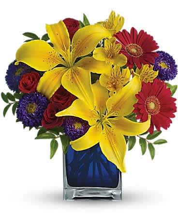 Bouquet of yellow lilies, red gerbera daisies, and purple flowers in a blue vase