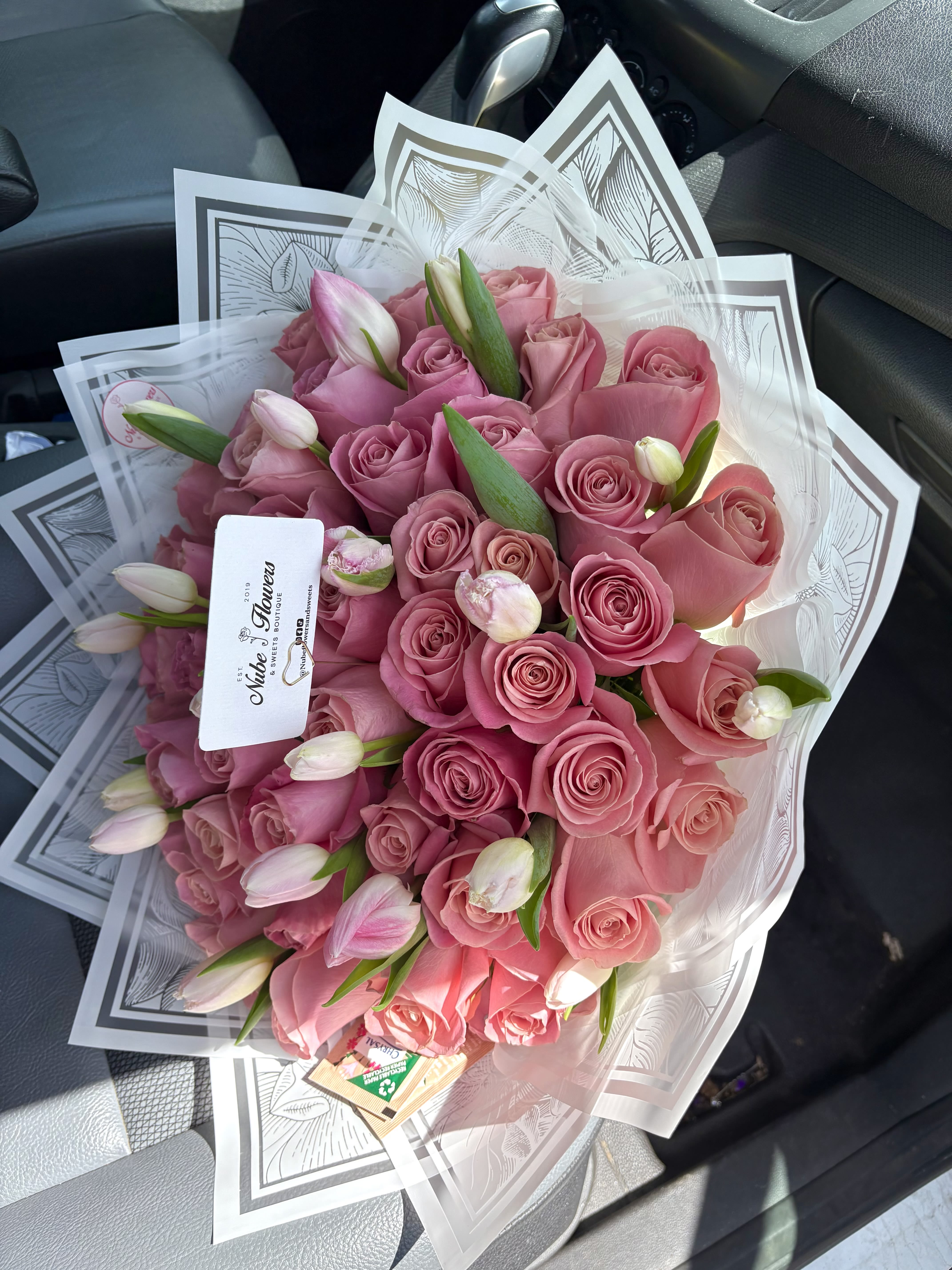 Bouquet of pink roses and tulip buds wrapped in clear paper