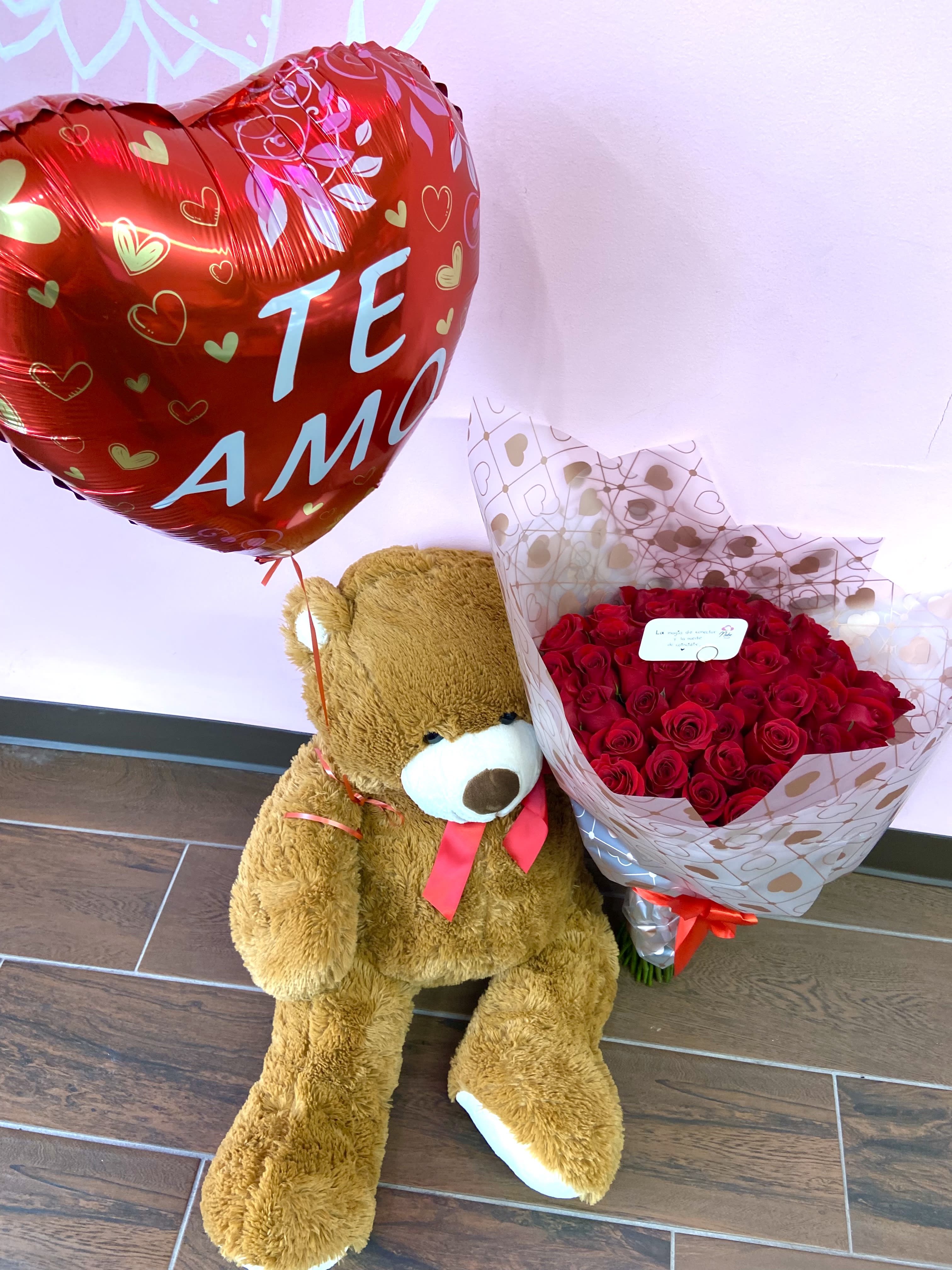 Teddy bear with a red heart balloon and bouquet of red roses