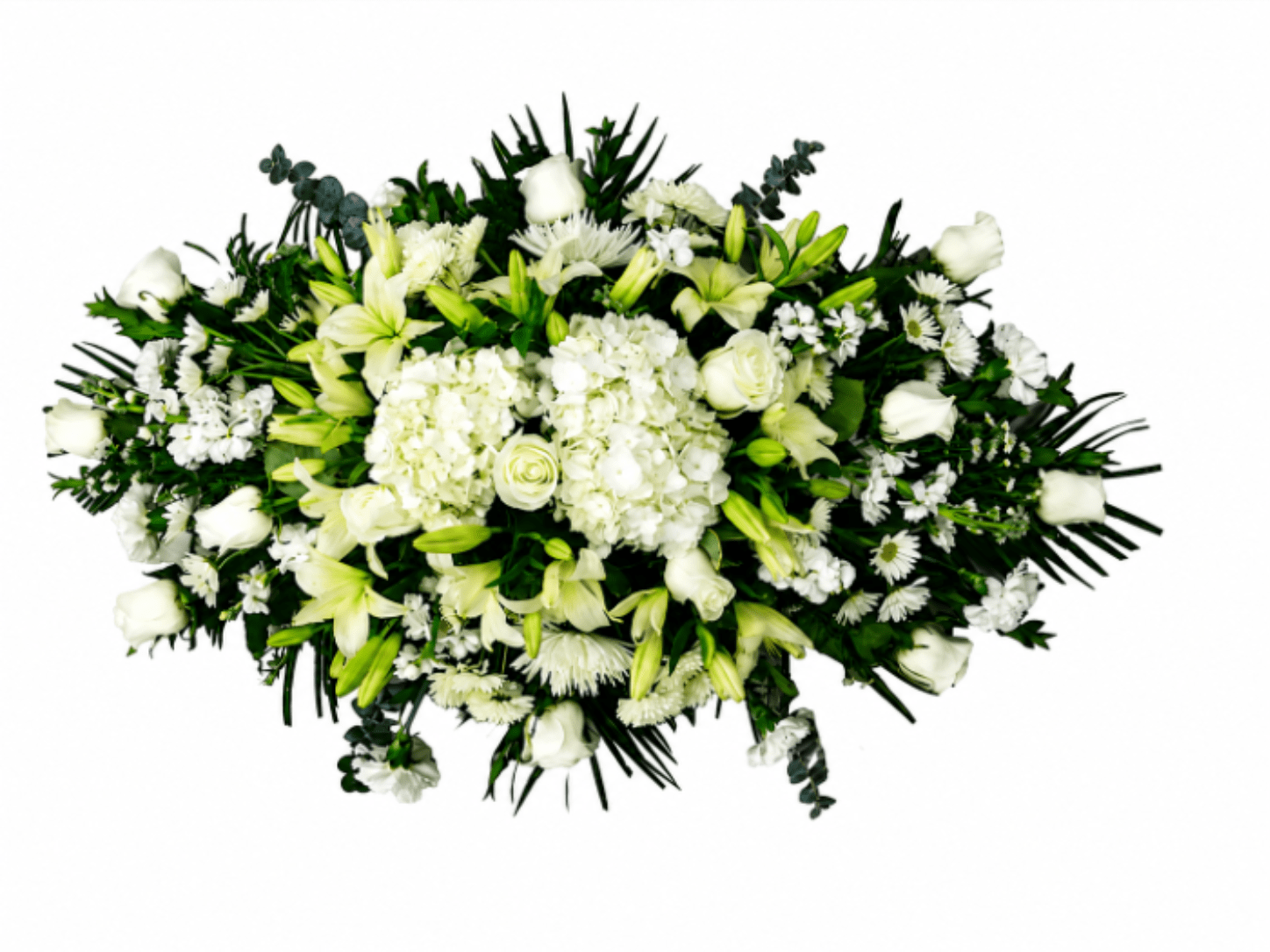 Eternal Peace - A serene, formal tribute crafted to honor a life: this sympathy flower arrangement features white roses and lilies layered with lush hydrangea clusters and delicate daisy-like blooms to create a dignified, elongated spray perfect for a funeral service or remembrance. The restrained palette of white and deep green foliage gives the piece a calming, timeless presence, so the person you're remembering will feel respected and cherished.  Generous in scale and arranged in a dense, layered teardrop or low horizontal form, the design pairs full-bodied white hydrangeas and roses with stately lilies, chrysanthemums, and small yellow-centered daisies for gentle contrast. Dark foliage frames the composition, emphasizing the arrangement's upright, substantial silhouette when used as a standing spray or as a casket adornment; the overall texture is lush yet composed, with each bloom placed to maintain a clean, formal line.  For memorial moments when words fall short, this arrangement offers a comforting, elegant way to express sympathy and remembrance for a loved one.