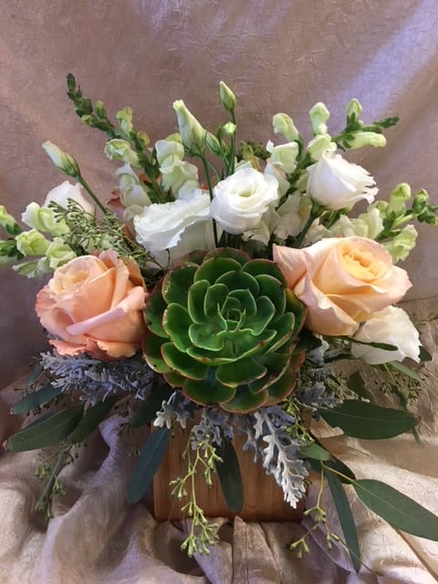 Peach and white roses with snapdragons and a green succulent in a wooden container