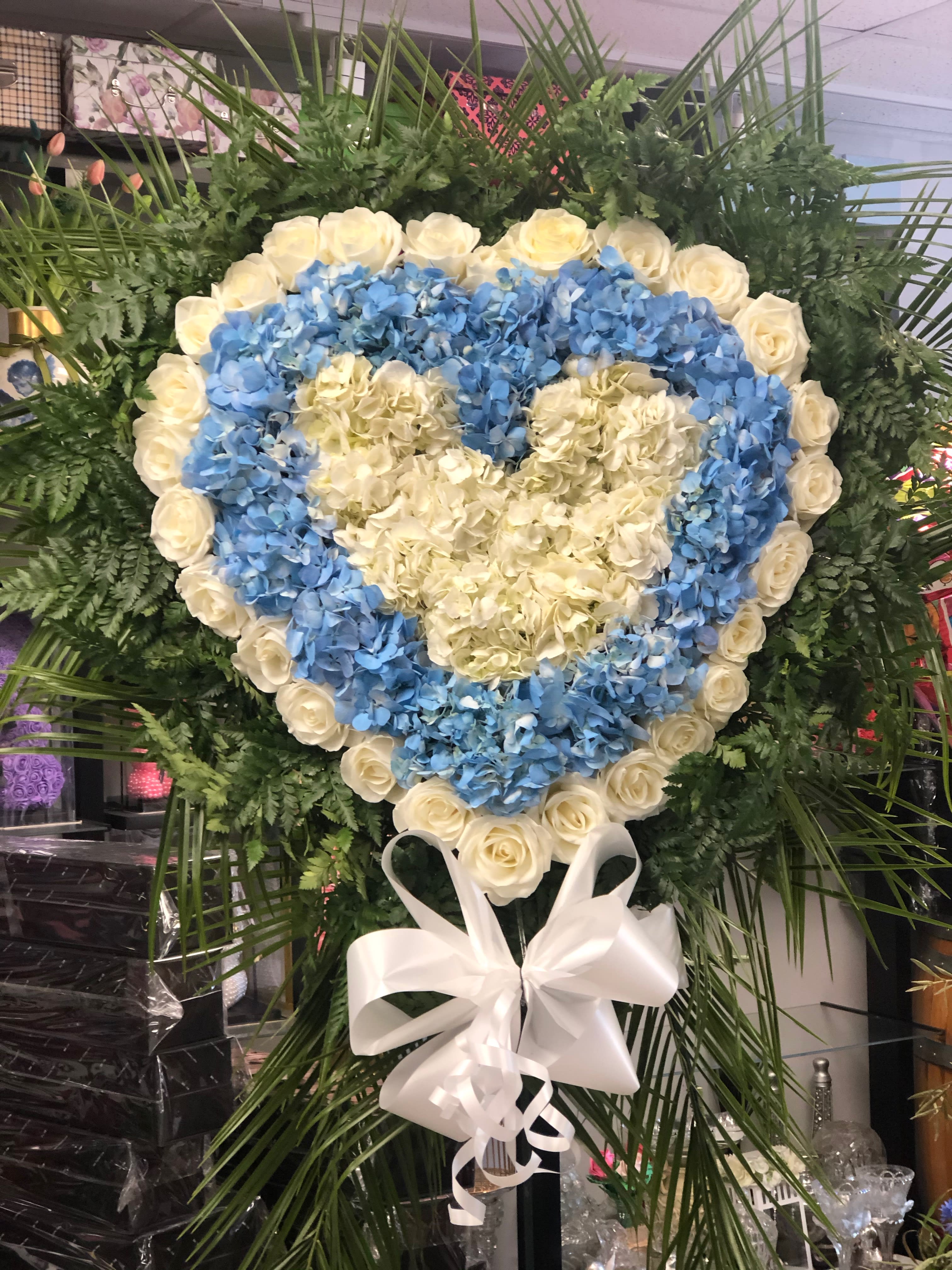 Heart-shaped floral wreath with blue hydrangeas and white roses, tied with a white bow