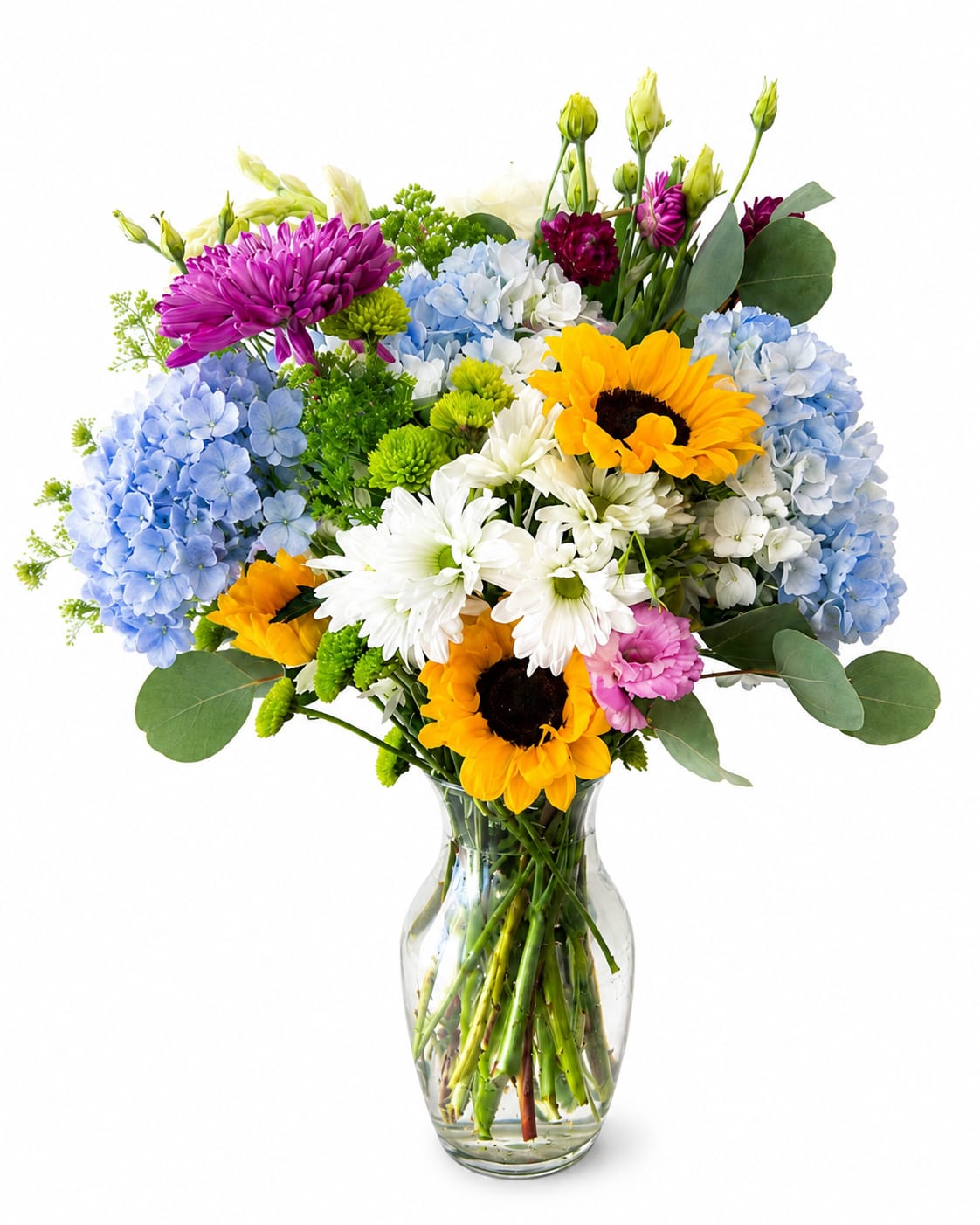 Country Cheer - Bright, sunny sunflowers steal the show in this country-style bouquet - a cheerful mixed-color arrangement perfect as a birthday bouquet, a thank-you gift, or a spring celebration centerpiece. The combination of yellow sunflowers, white chrysanthemums, pale blue hydrangeas, purple mums, and pink lisianthus creates an upbeat, homey vibe that will make the person you're thinking of feel noticed and genuinely brightened.  Layered at different heights for a full, airy garden look, the bouquet arrives in a clear glass vase that lets the stems and water add to the casual, rustic charm. Textures range from the broad, bold sunflower faces to the soft clusters of hydrangea and the delicate lisianthus, giving it a playful, textured silhouette that works well on a kitchen table or as a cheerful desk pick-me-up.  Because the design reads as an everyday bouquet, it's ideal for neighbors, teachers, or friends who appreciate a joyful, no-fuss arrangement. Standard care: keep in fresh water and trim stems every few days to help blooms last longer; ordering is available for same-week delivery so your recipient can enjoy peak bloom.
