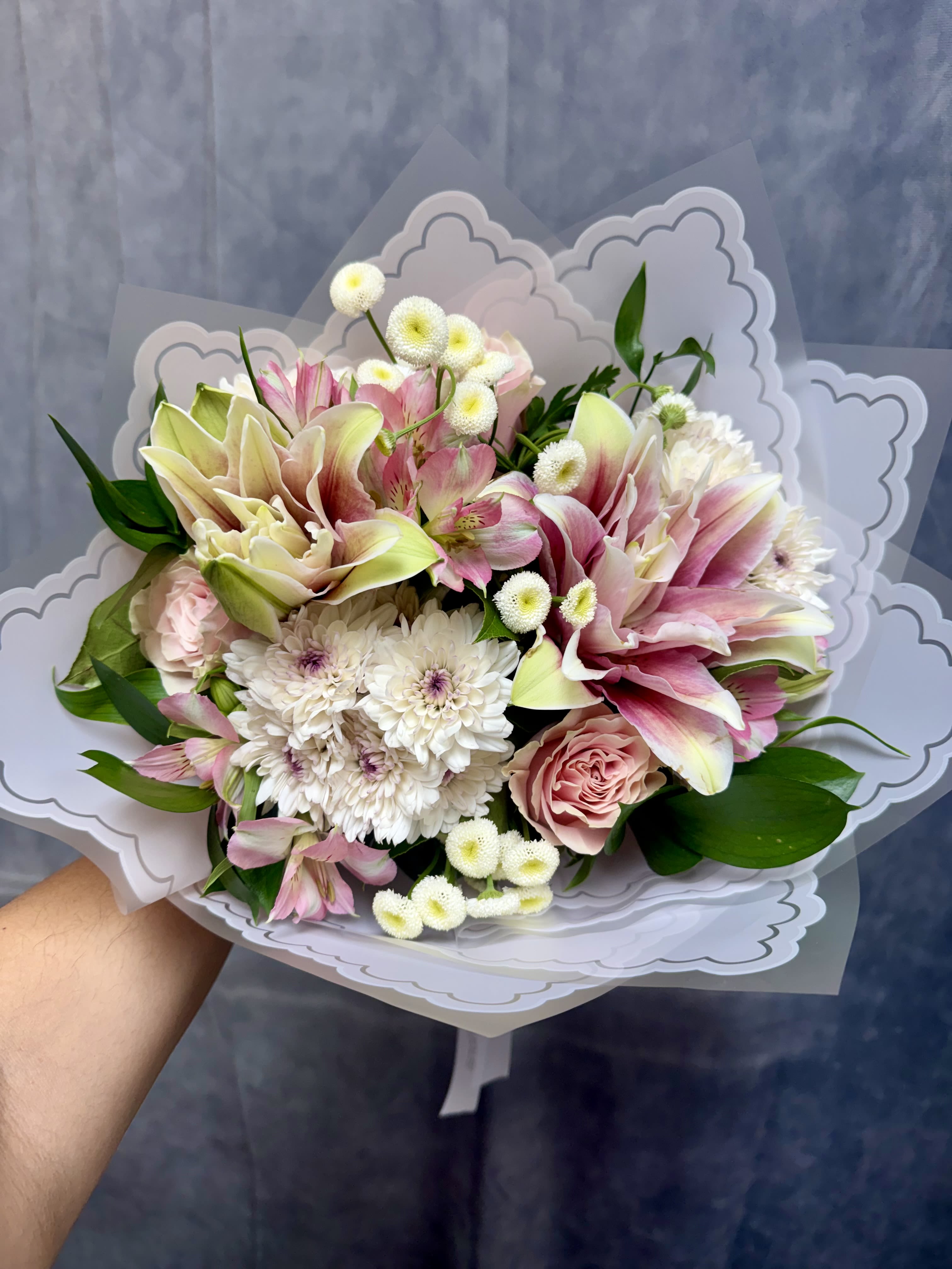 Pink Lovers Bouquet  - A romantic blend of soft pink lilies, blush roses, delicate alstroemeria, dainty button mums, and fresh greenery, beautifully wrapped in elegant decorative paper. Full of grace and charm, this bouquet is the perfect way to express love, appreciation, and heartfelt affection for any special occasion. 