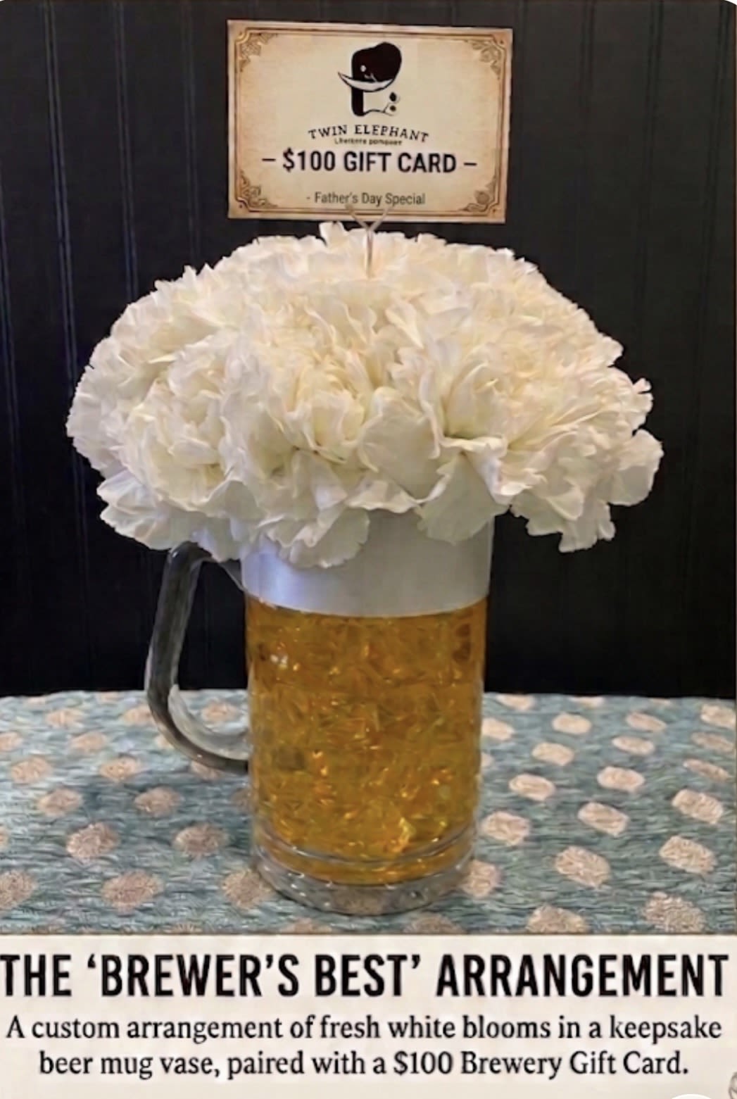 Brewer's Best - BREWERY GIFT CARD ADD ON AVAILABLE  - A rounded cloud of white carnations sits cheerfully in a clear beer mug vase, making this flower arrangement an ideal brewery-themed gift or Father's Day bouquet that feels casual, fun, and thoughtful. The beer mug presentation and the included gift card sign make the intent obvious: a playful way to celebrate the dad, friend, or host who loves craft beer while keeping the look clean and versatile.  