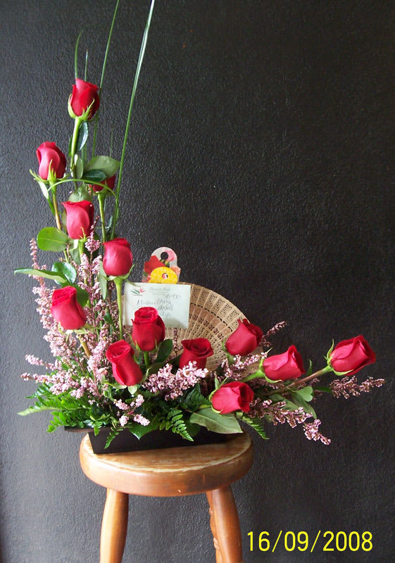 Red roses arranged in a low black container with pink filler flowers