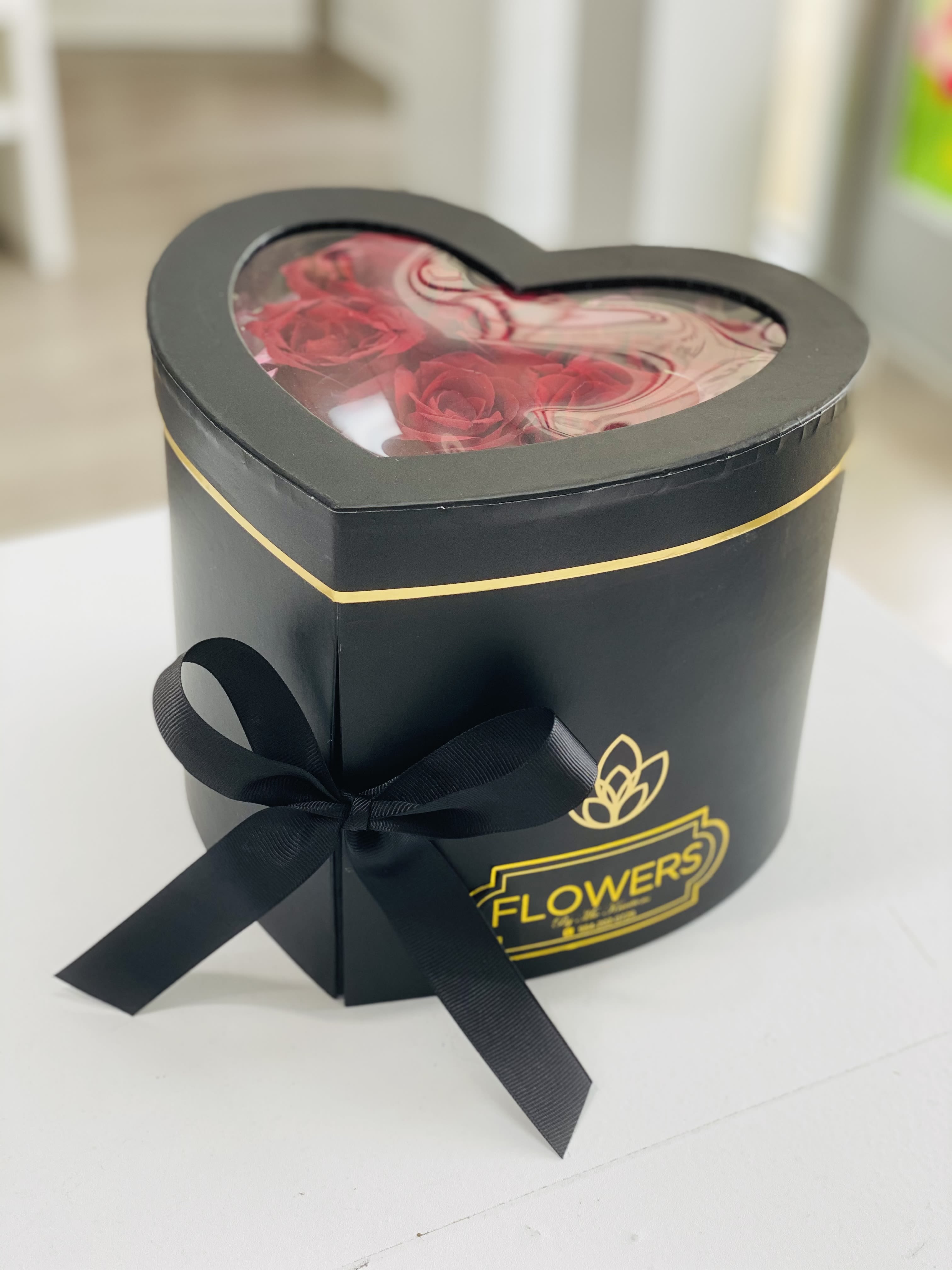 Heart-shaped black gift box with red roses and a ribbon bow