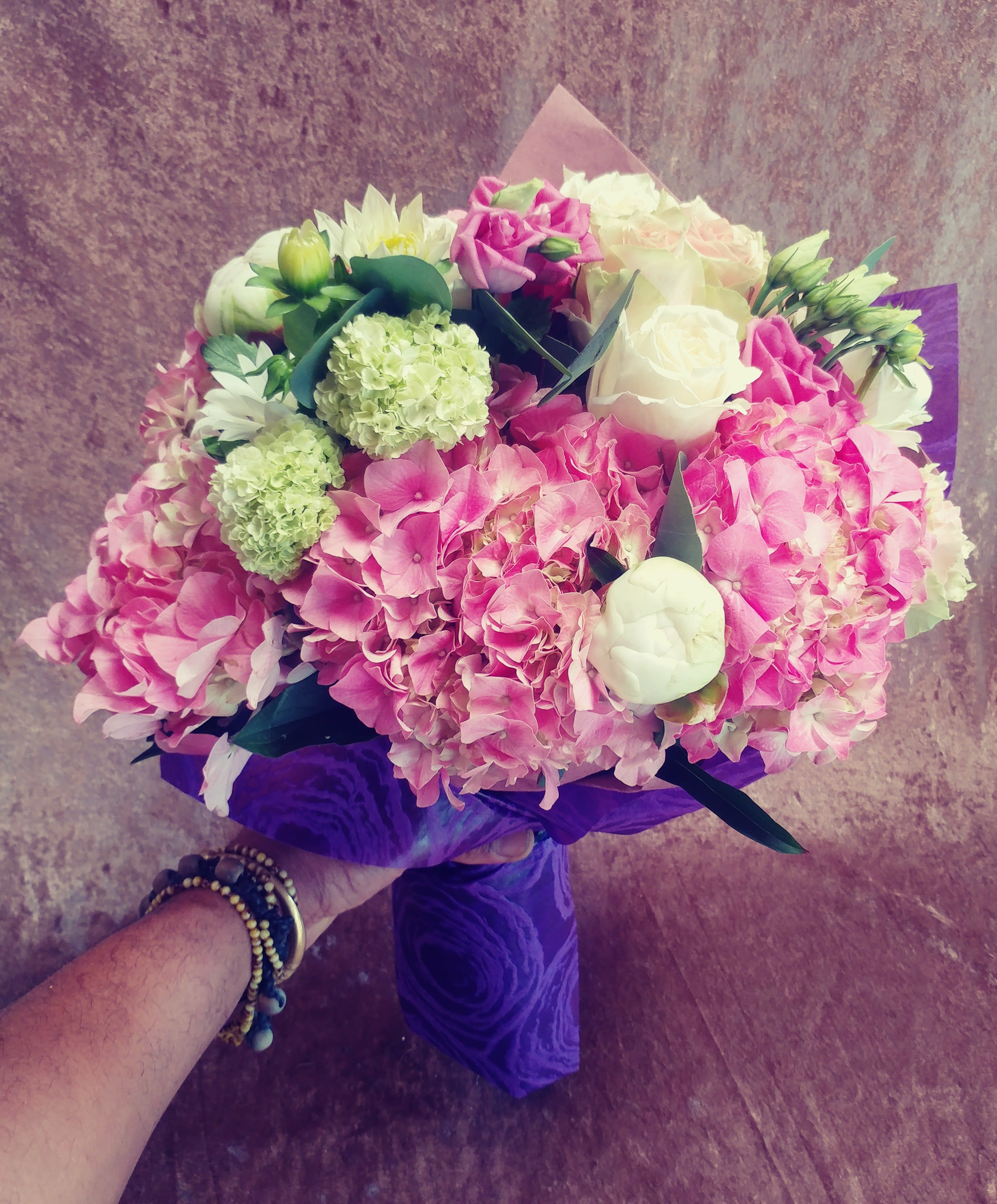 Pink and white bouquet with hydrangeas and roses wrapped in purple paper