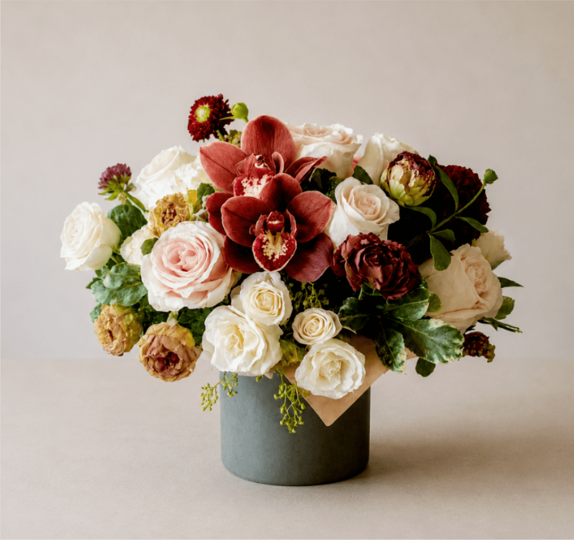 Bouquet of roses and burgundy orchids in a gray vase