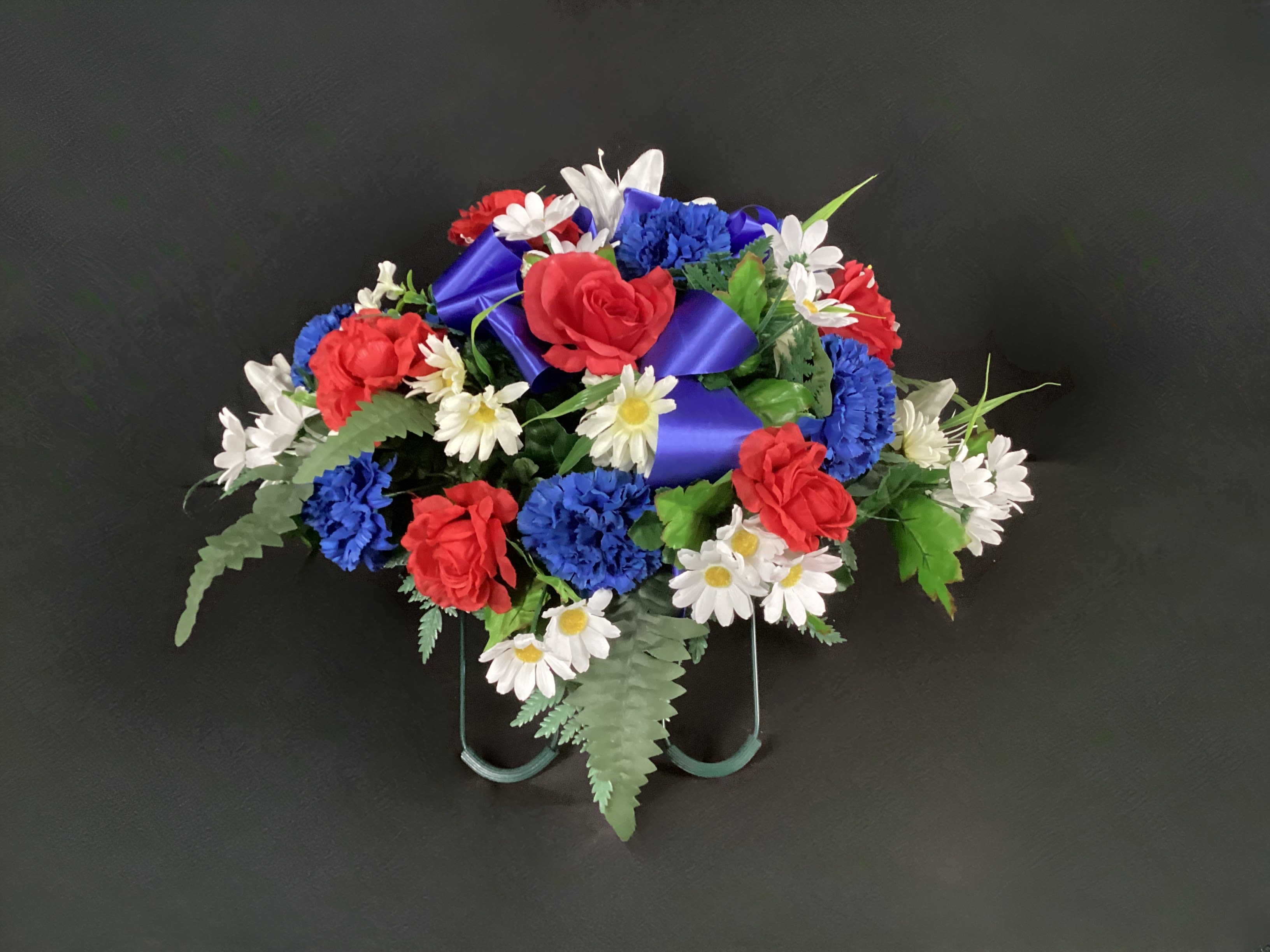 Red, white, and blue floral arrangement with a purple ribbon on a stand