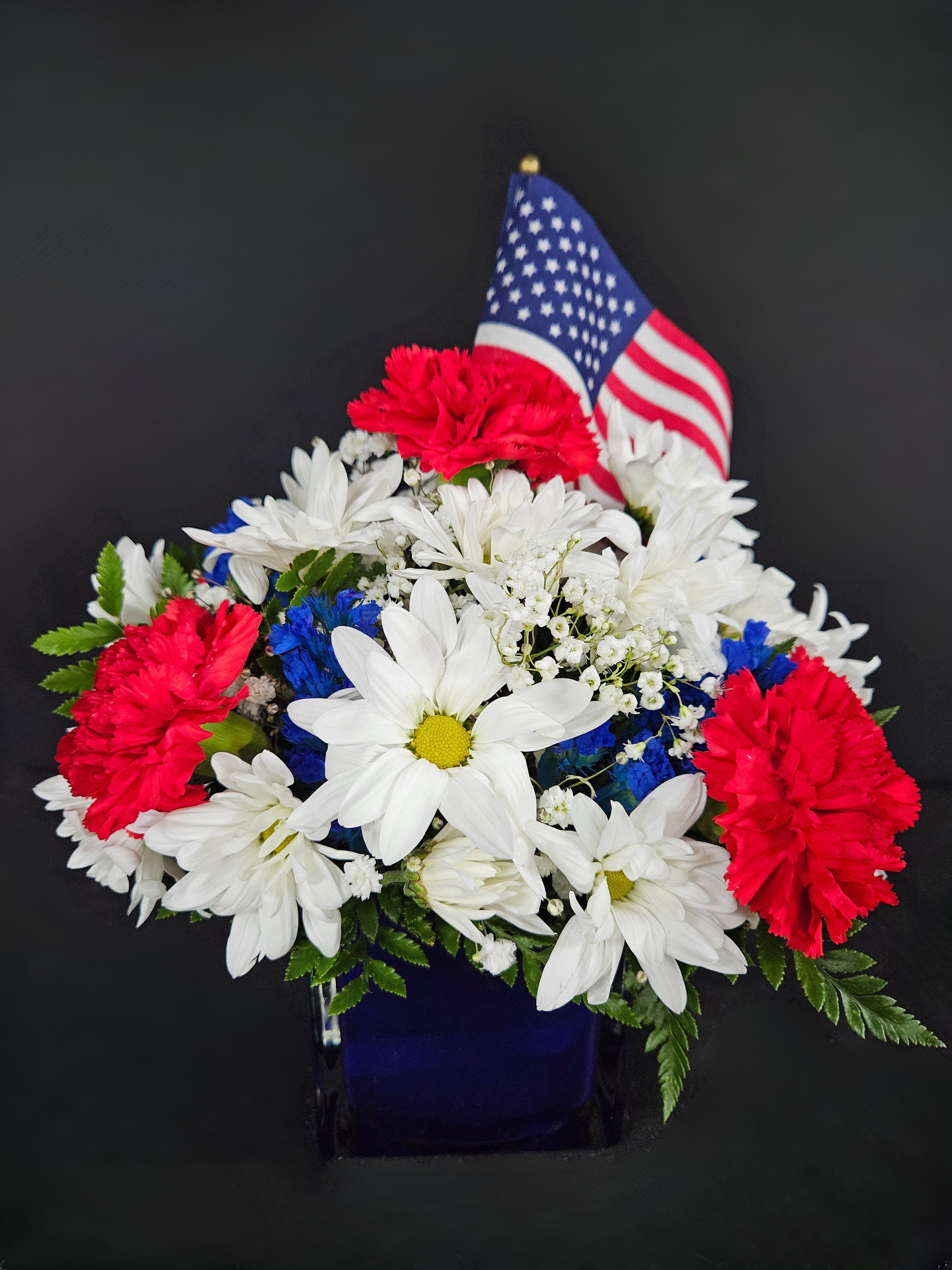 Red, white, and blue flower arrangement with an American flag