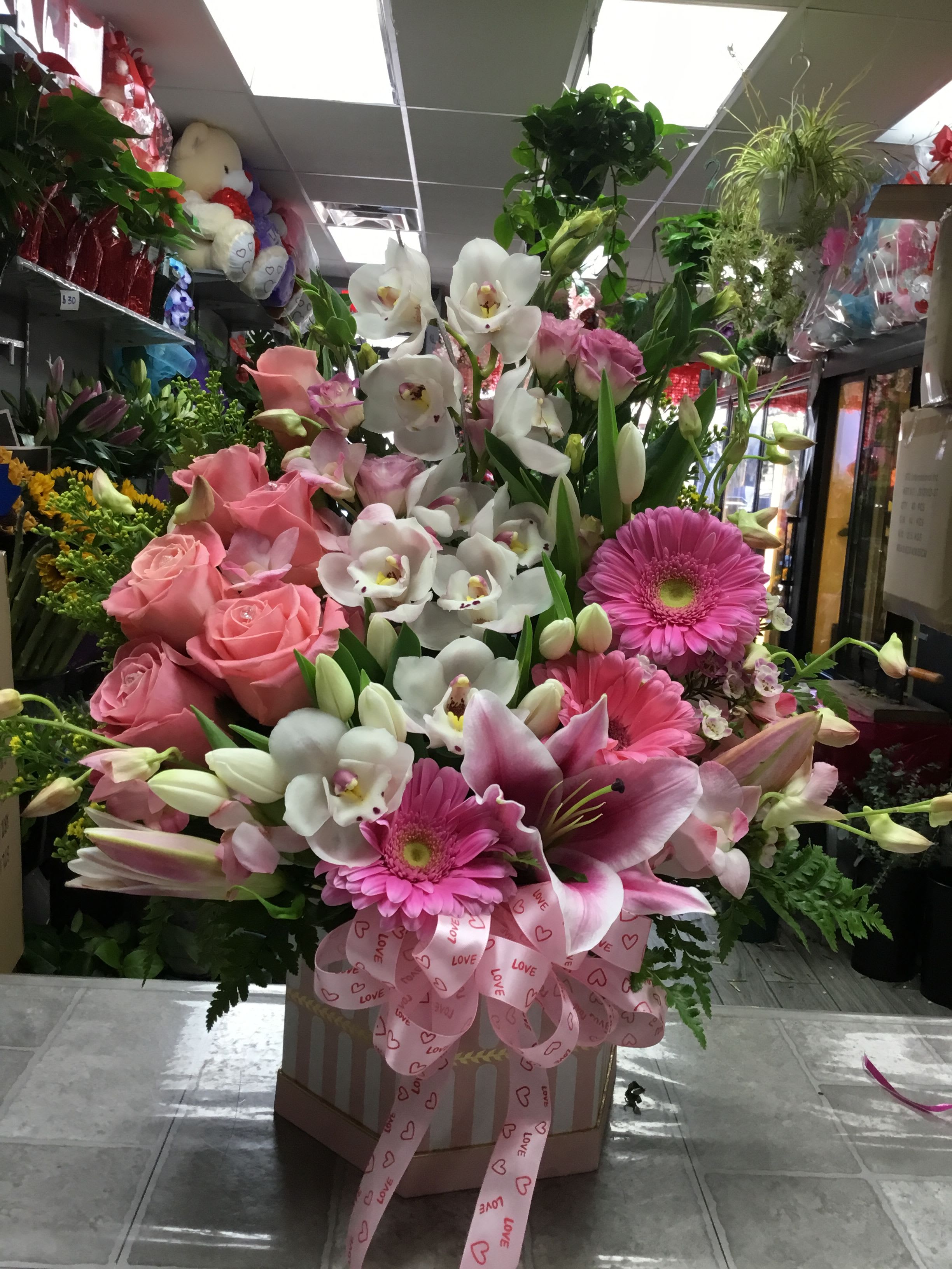 Pink and white mixed flower arrangement in a box with a pink ribbon