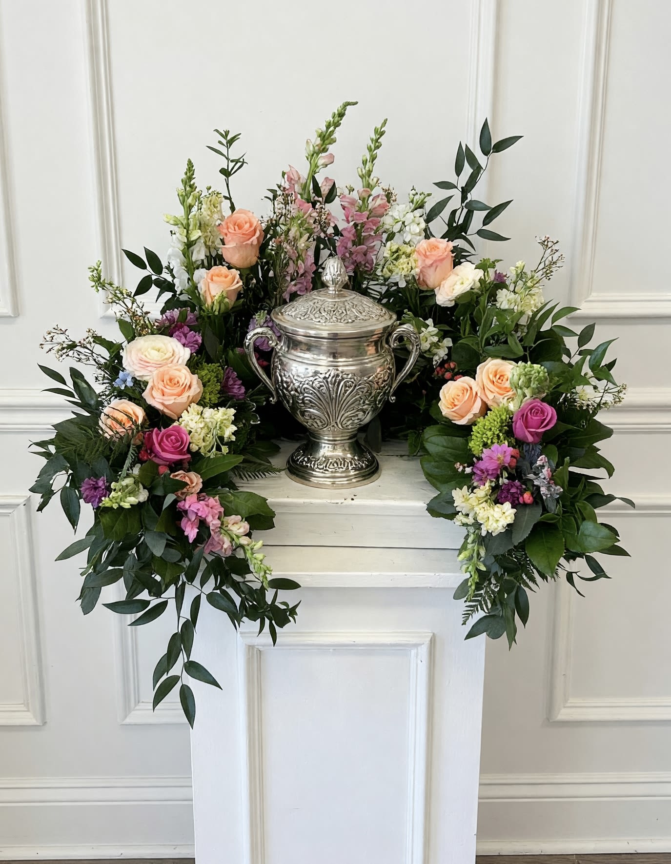 Everlasting Embrace  - This cremation urn arrangement is designed to surround the urn with an abundant garden of blooms. Seasonal stems and greenery are artfully arranged to create natural frame that draws the eye to the cherished urn at the center. Suitable for wake services, funeral gatherings or celebration-of-life ceremonies.   Please call the shop directly to discuss specifics and color palettes. *Urn not included. 