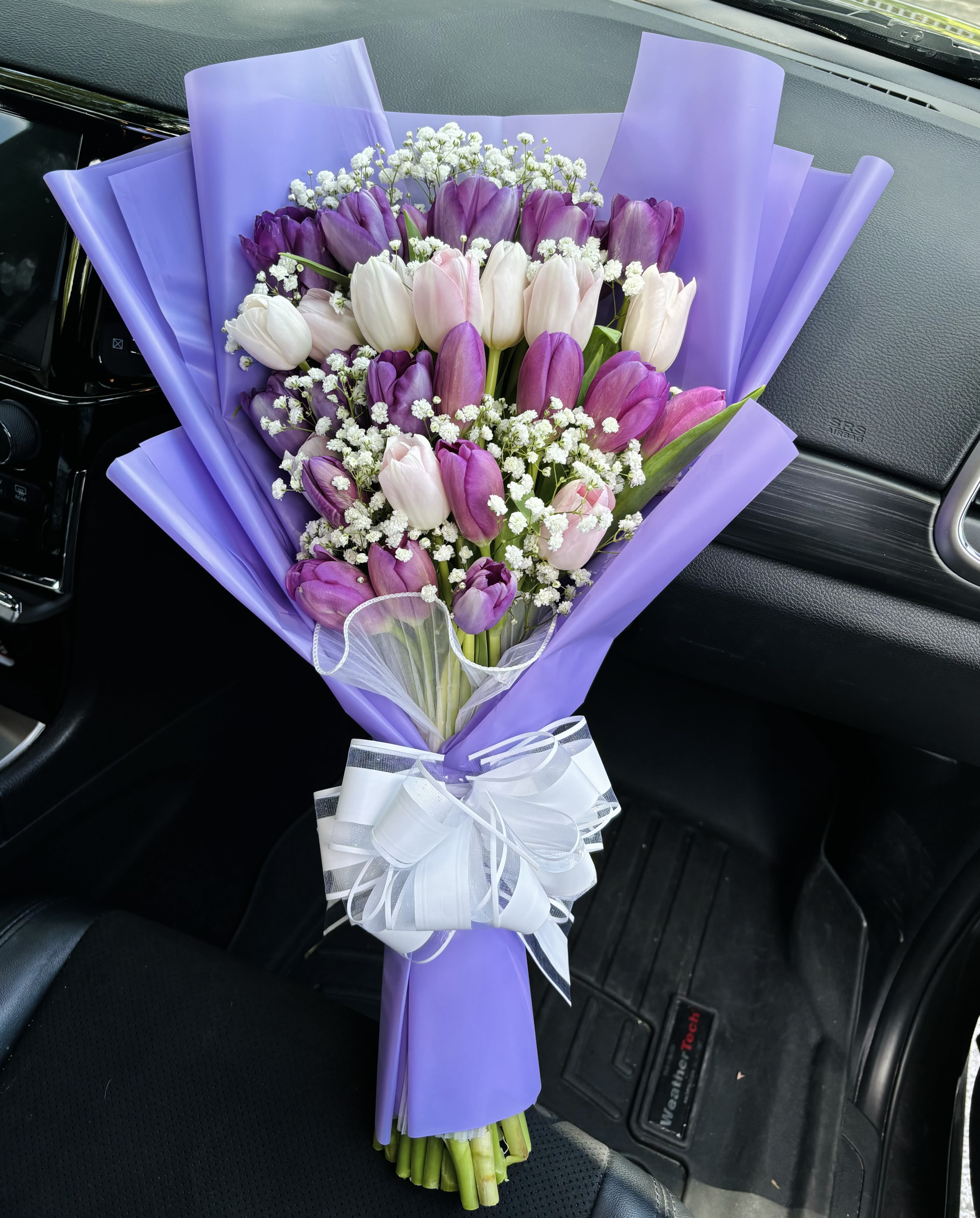 Bouquet of purple, pink, and white tulips wrapped in lavender paper