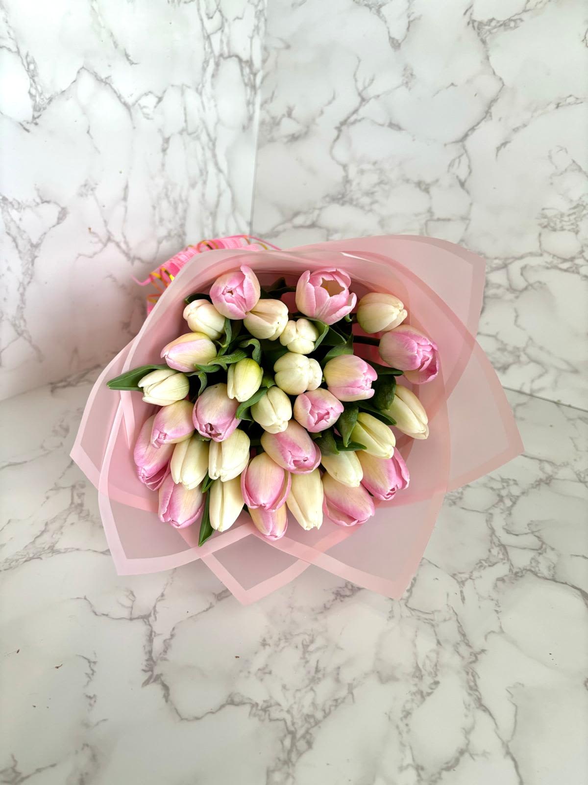 Bouquet of pink and cream tulips wrapped in pale pink paper