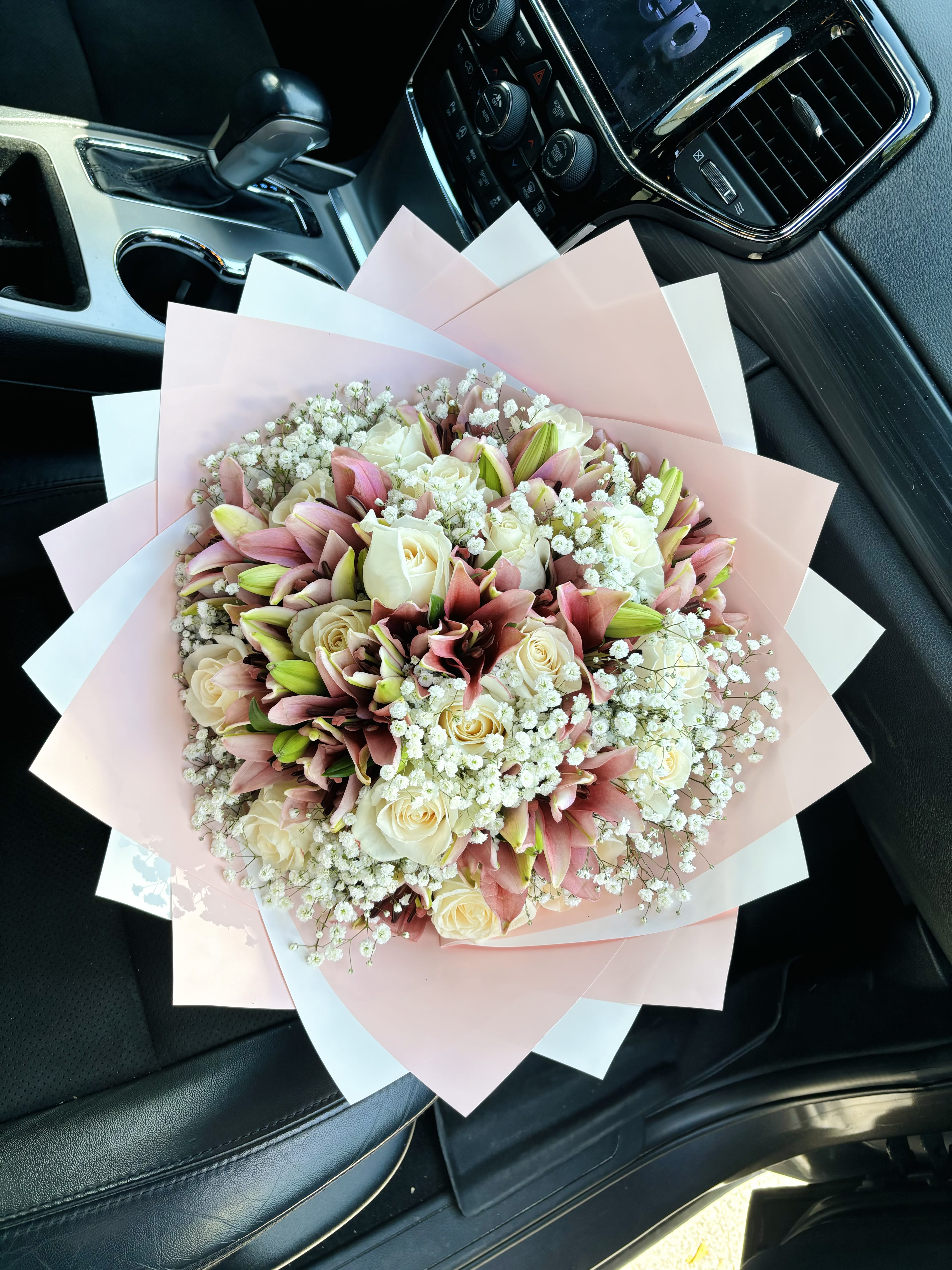 Bouquet of pink lilies and cream roses wrapped in pastel paper