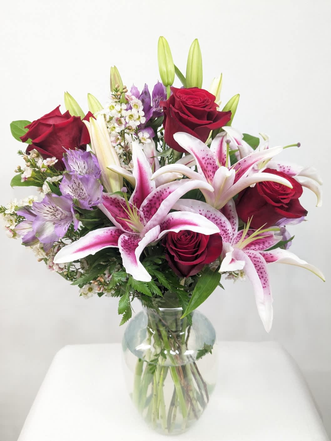 Bouquet of red roses and pink lilies in a clear glass vase