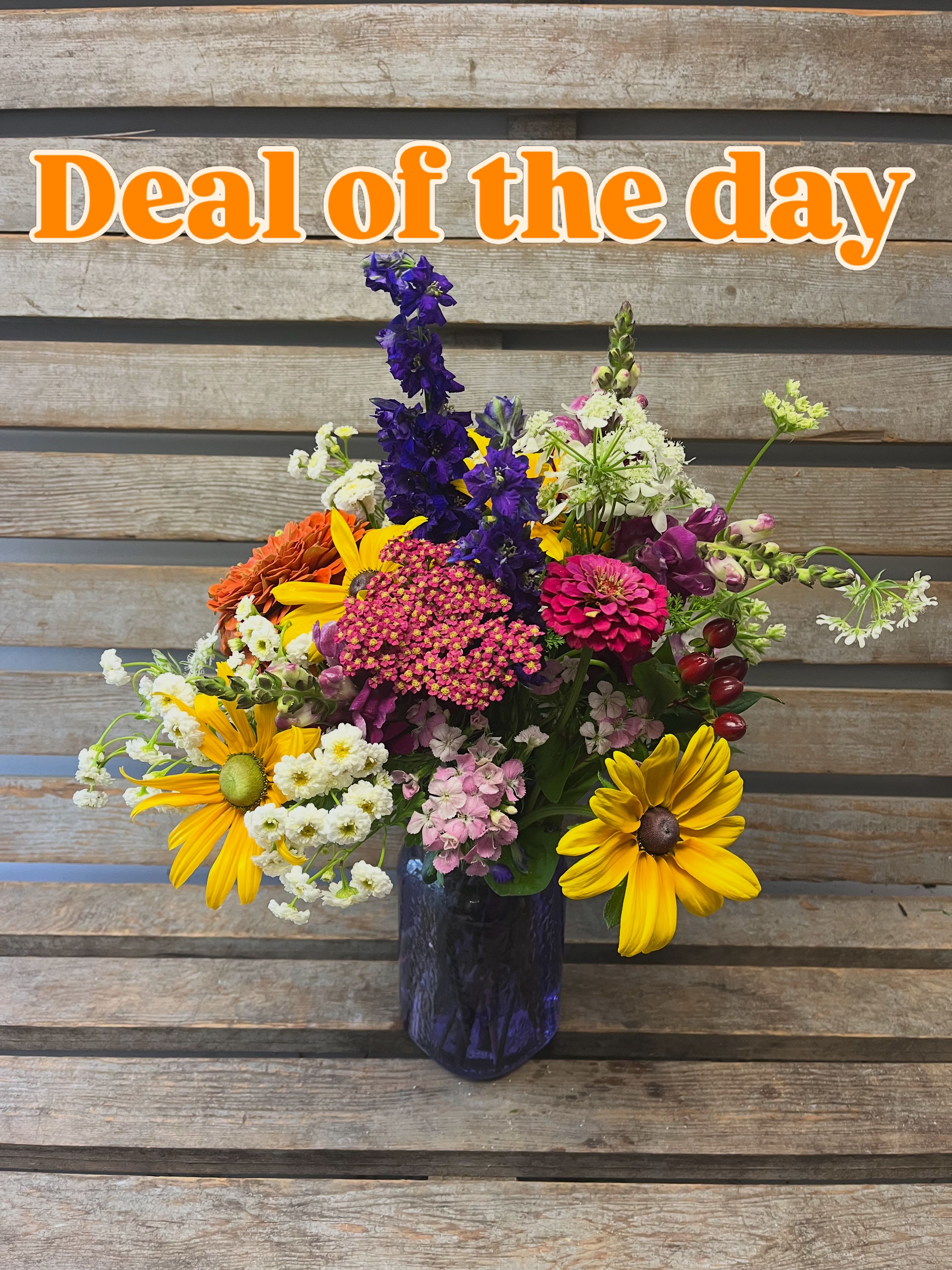 Summer mason jar ( asst color jar)  - Sunshine-yellow daisies and vivid purple snapdragon spikes burst from a deep blue glass mason jar to create a lively summer flower arrangement perfect for everyday gifting or a cheerful birthday bouquet. This mixed-color flower arrangement reads like a casual garden-picked posy-bright, informal, and made to make the person you're thinking of feel seen and celebrated.  The design pairs yellow daisy-like blooms with tall purple snapdragons, soft white filler stock, and pink accents for a pleasing mix of texture and color. Arranged loosely in an asymmetrical, full composition, several stems extend outward for a relaxed, natural silhouette. Housed in a blue glass vase, the piece measures as a hand-tied, medium-style arrangement suited for tabletops, entryways, or bedside tables.  Send it to a friend, parent, or coworker to mark a summer get-together, a small milestone, or simply because you're thinking of them-this is the kind of bouquet that brightens a day without fuss. For best enjoyment, keep the water fresh and display away from direct heat; replace water and trim stems every few days to extend the life of the blooms.