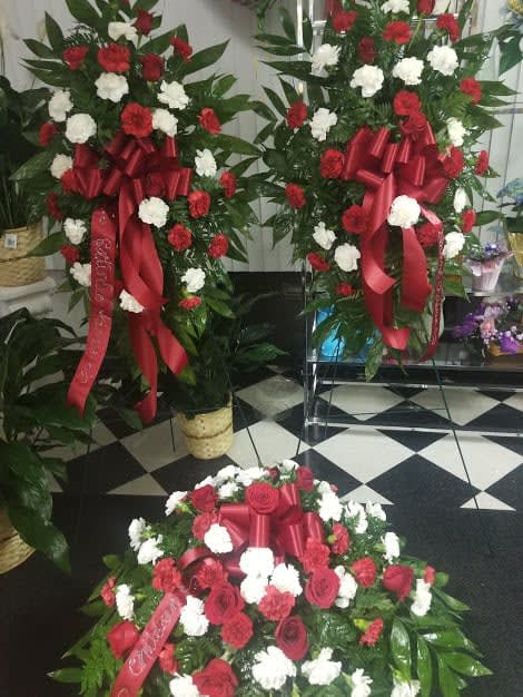 Three red and white floral standing sprays with ribbon bows