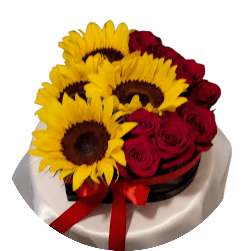Eclipse - Sunflowers and deep red roses collide in a bold, romantic display made for anniversaries, birthdays, or any moment you want the person you're thinking of to feel both celebrated and adored. This flower arrangement for love or special occasions pairs cheerful yellow sunflower faces with clustered red roses, creating a dramatic color story of yellow, red, black, and white that reads as joyful and luxurious at once.  The blooms are arranged compactly in a round black hat box, accented with a red satin ribbon and set against draped white fabric for striking contrast. Low and round in presentation, the composition highlights the texture of sunflower centers and the velvety rose petals, making a strong visual impact while remaining easy to display on a table or desk. Send this when you want them to feel truly seen-vibrant, romantic, and celebrated.