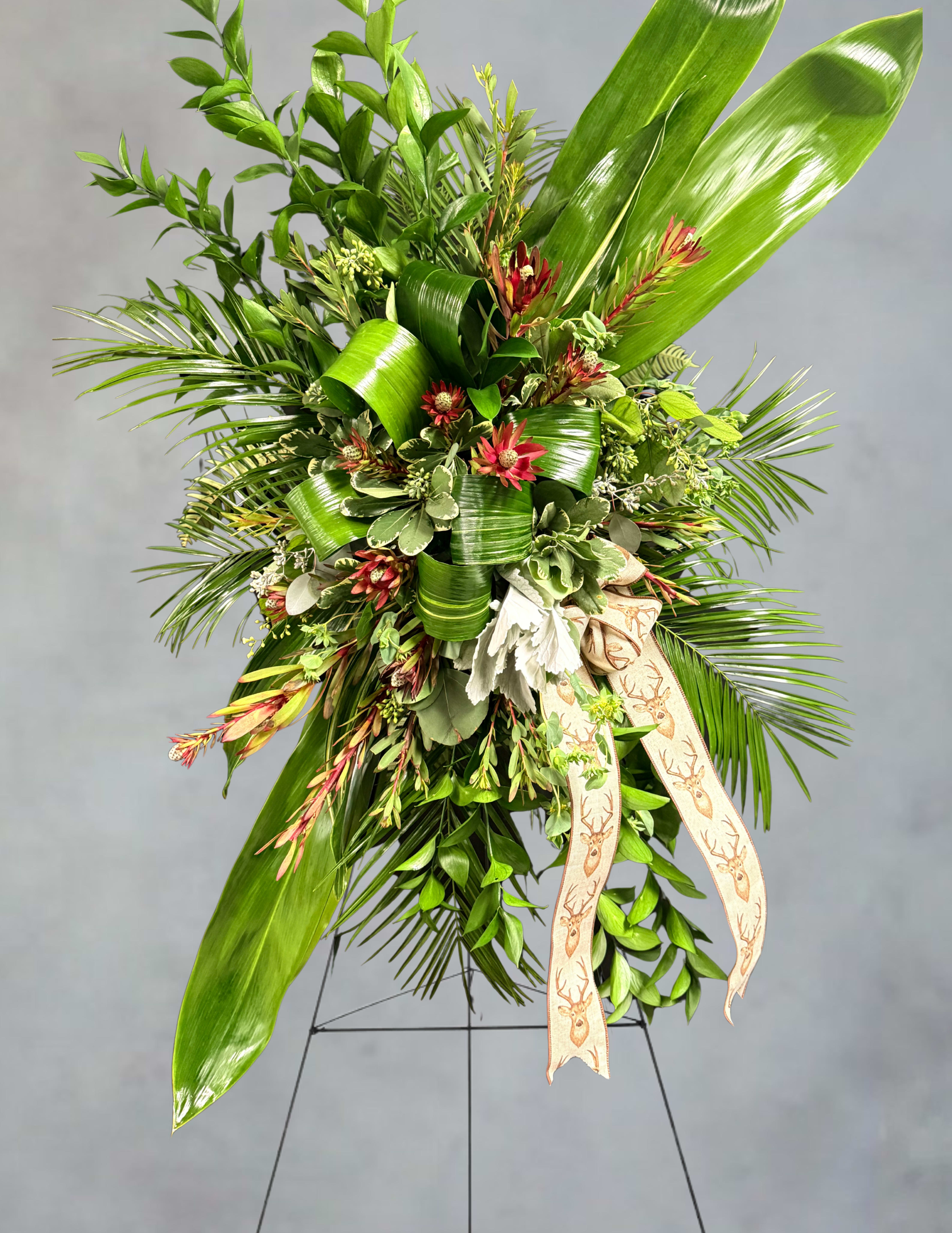 Large green floral spray with red accents and a deer-print ribbon