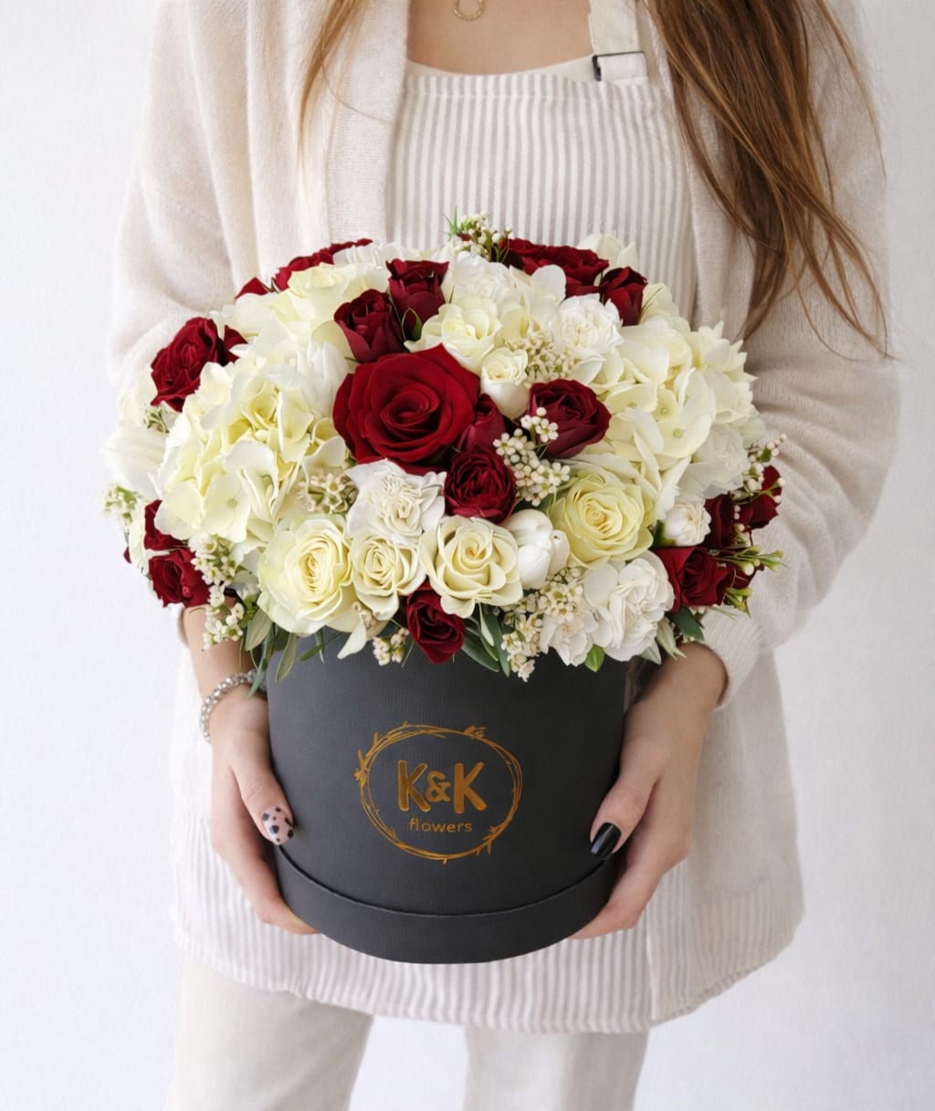 Red and white roses arranged in a black round box