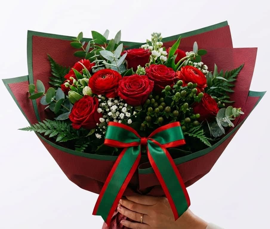Atlas Lions - Morocco  - Vivid red roses take center stage in this Atlas Lions - Morocco flower arrangement, a bold bouquet designed for celebratory gifting and perfect for a FIFA World Cup fan. The red-green-white palette-rich scarlet roses, bright white filler blooms, and lush mixed greenery-creates a festive, spirited look that reads both romantic and proudly team-focused for match-day cheering or victory celebrations.  Carefully hand-tied in a full, rounded style, each rose is curated for a dense, polished appearance and accented with delicate white filler flowers for contrast and texture. The stems are finished in a deep red decorative paper wrap with green edging and a coordinating red-and-green satin ribbon, giving the bouquet a luxe, gift-ready presentation that echoes Morocco's colors while remaining elegant enough for anniversary or congratulatory occasions.  Send this arrangement to make the person you're thinking of feel celebrated and seen-whether it's to boost pre-game excitement, mark a win, or simply show support. The designer's personal touch is evident in the curated placement of each bloom; order with standard sizing as shown and enjoy simple care: keep stems trimmed, fresh water changed regularly, and display away from direct heat to extend the life of the roses.
