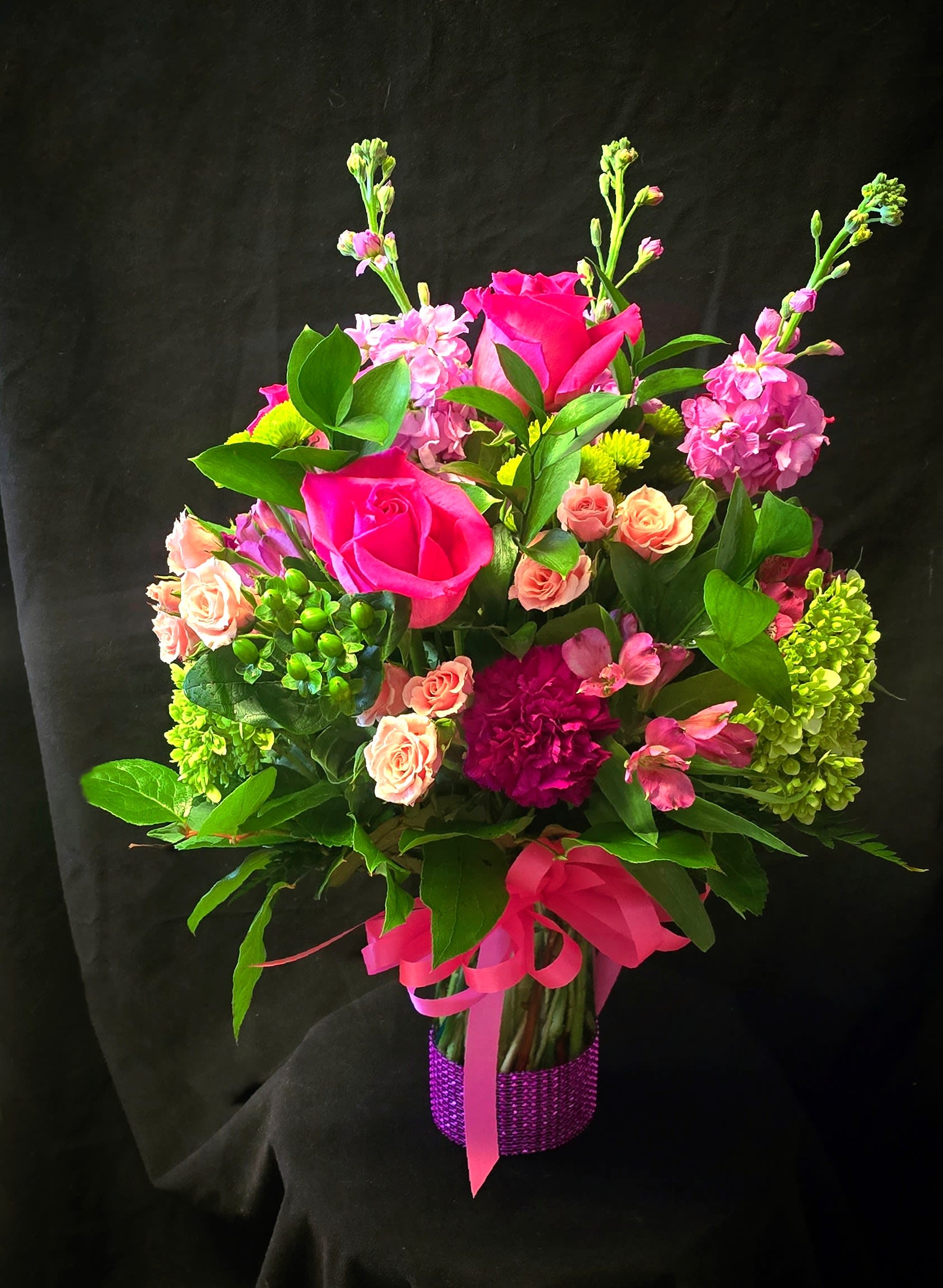 Pink and peach flower bouquet in a purple wrapped vase
