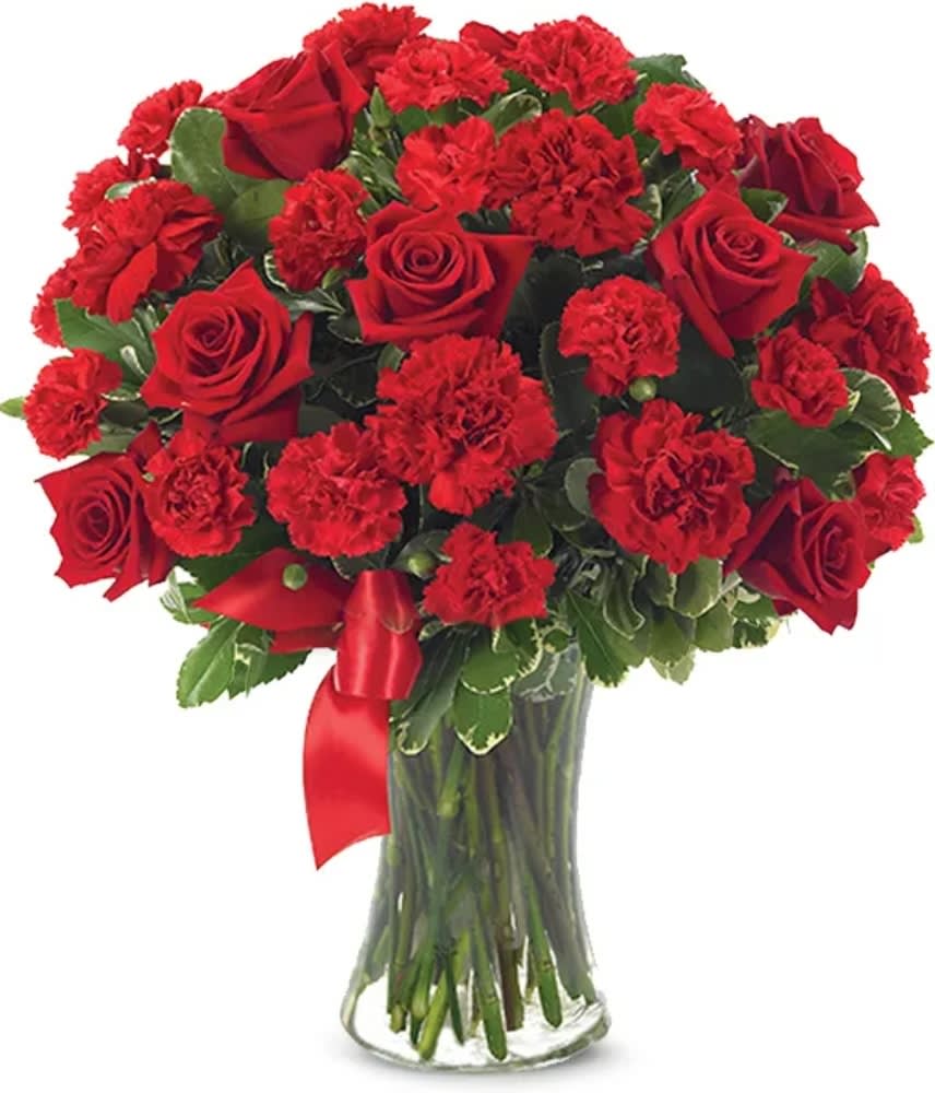 Red roses and carnations in a clear glass vase with a red ribbon