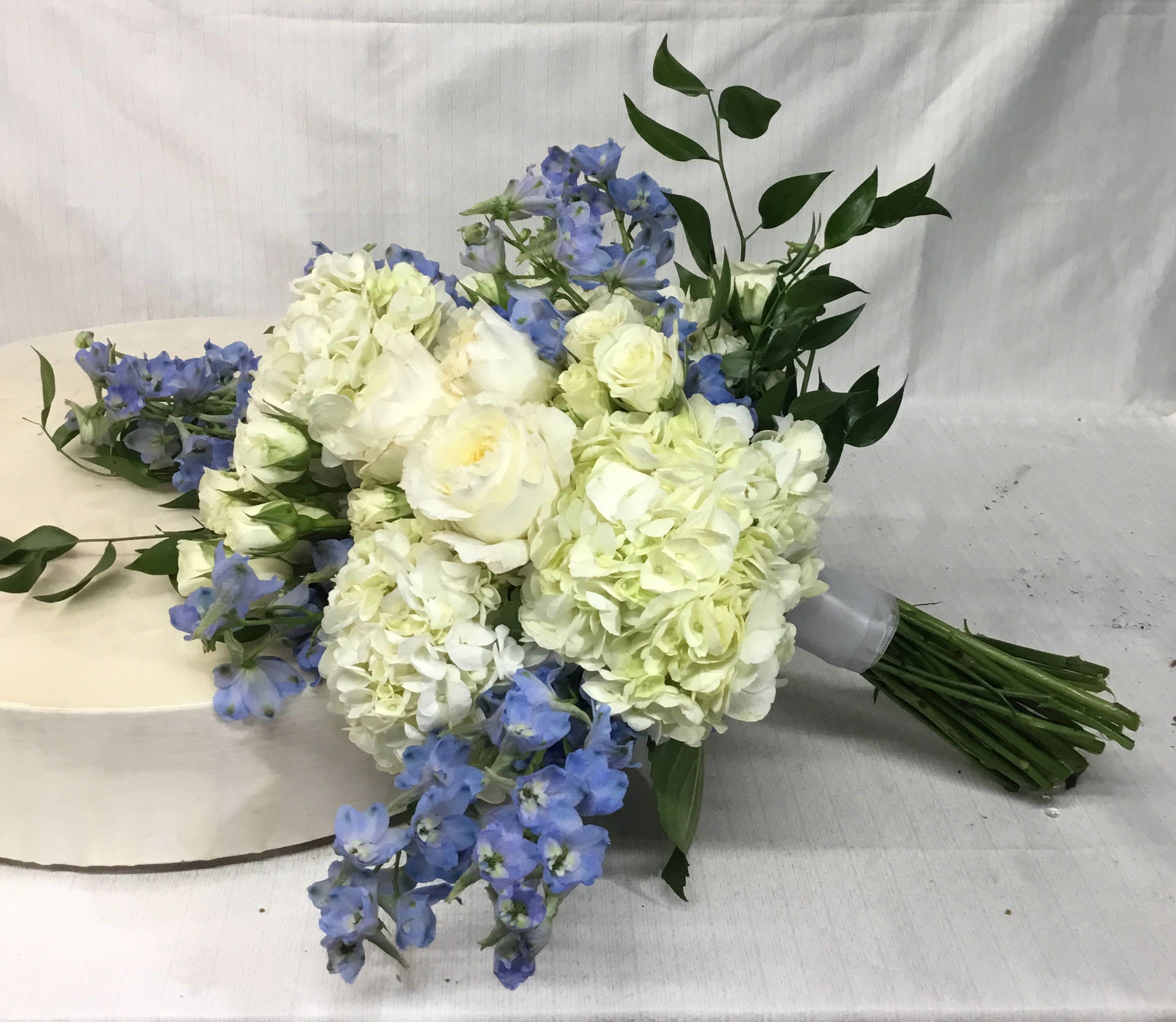 Bouquet of white hydrangeas and blue flowers with greenery