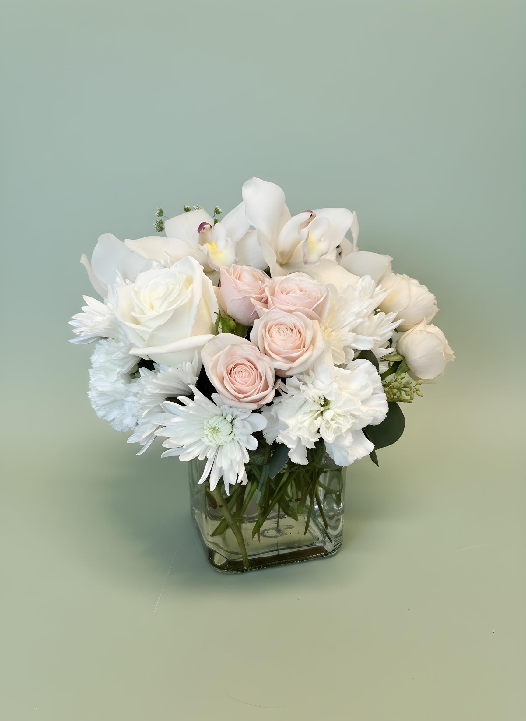 Blushing Elegance Bouquet - Soft, romantic, and timeless, our Blushing Elegance Bouquet is designed with premium white roses, blush roses, white mums, cymbidium orchids, carnations, and seasonal blooms arranged in a modern glass vase. This graceful floral design captures the beauty of love, appreciation, and heartfelt sentiment.  Perfect for birthdays, anniversaries, sympathy gifts, get well wishes, baby showers, bridal showers, or simply letting someone know they’re loved. The delicate blush and white color palette creates a sophisticated look that complements any home, office, or special occasion. Handcrafted with care by Tommy Austin Florist and available for local flower delivery throughout Rancho Cucamonga, Ontario, Upland, Claremont, Fontana, and surrounding Inland Empire communities. Perfect For • Birthday Flowers • Anniversary Flowers • Sympathy &amp; Thinking of You Gifts • Baby Girl Celebrations • Bridal Showers • Mother’s Day Flowers • Just Because Gift