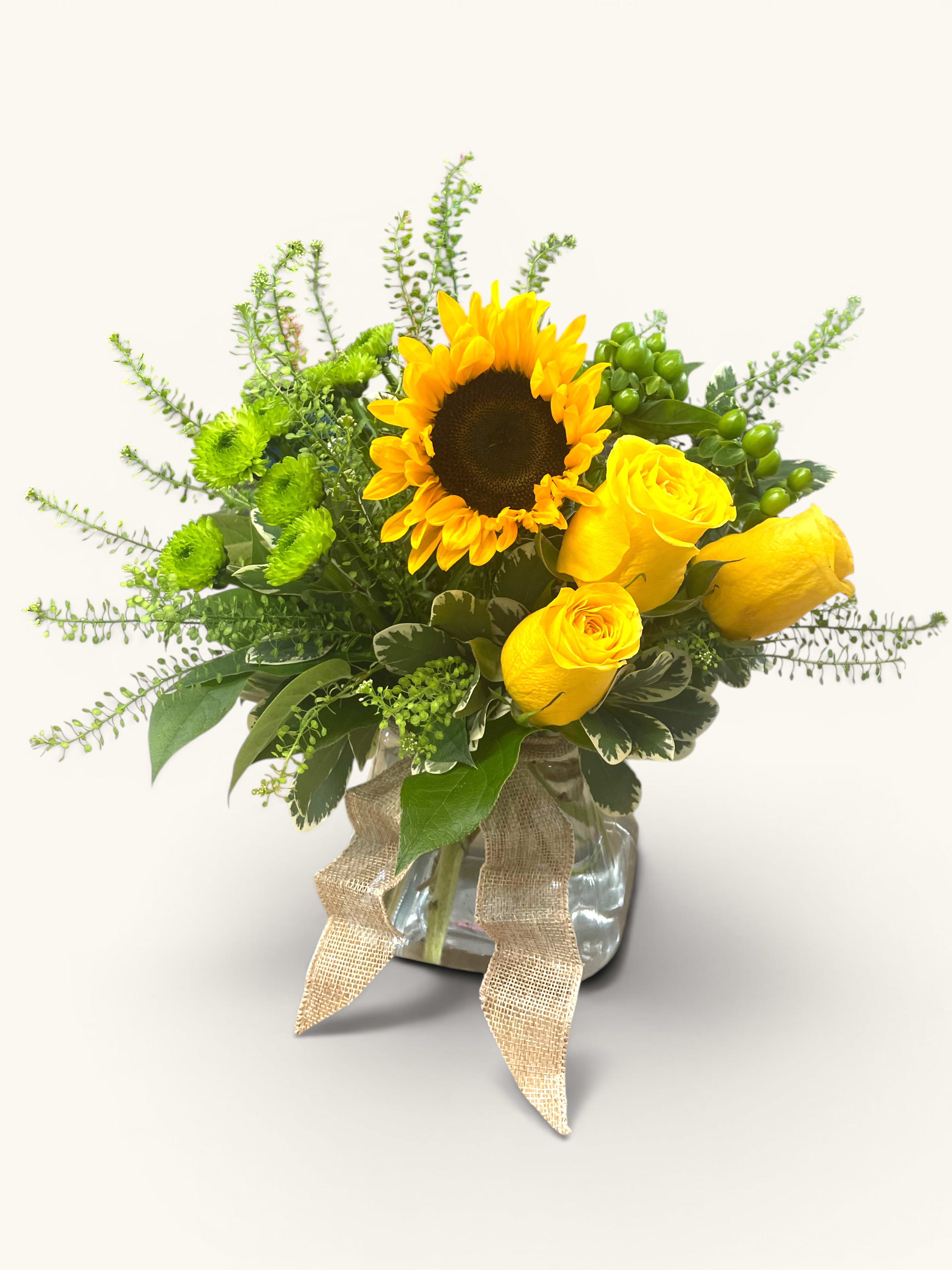 Bring The Sunshine Vase - Radiant yellow roses and cheerful sunflowers, complemented by vibrant green mums, create a joyful arrangement that’s sure to lift spirits and bring a smile to anyone’s face!