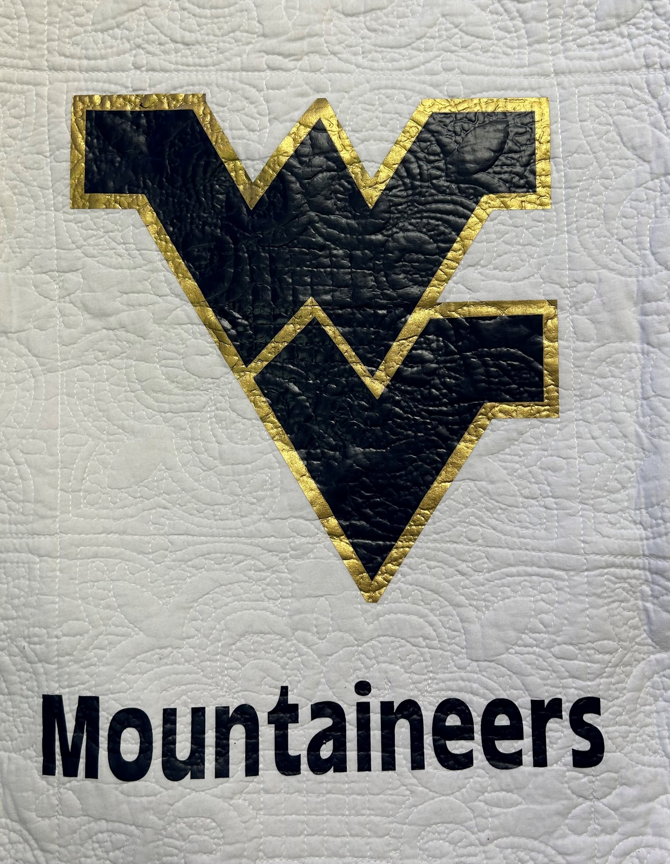 Quilted West Virginia Mountaineers logo on white fabric