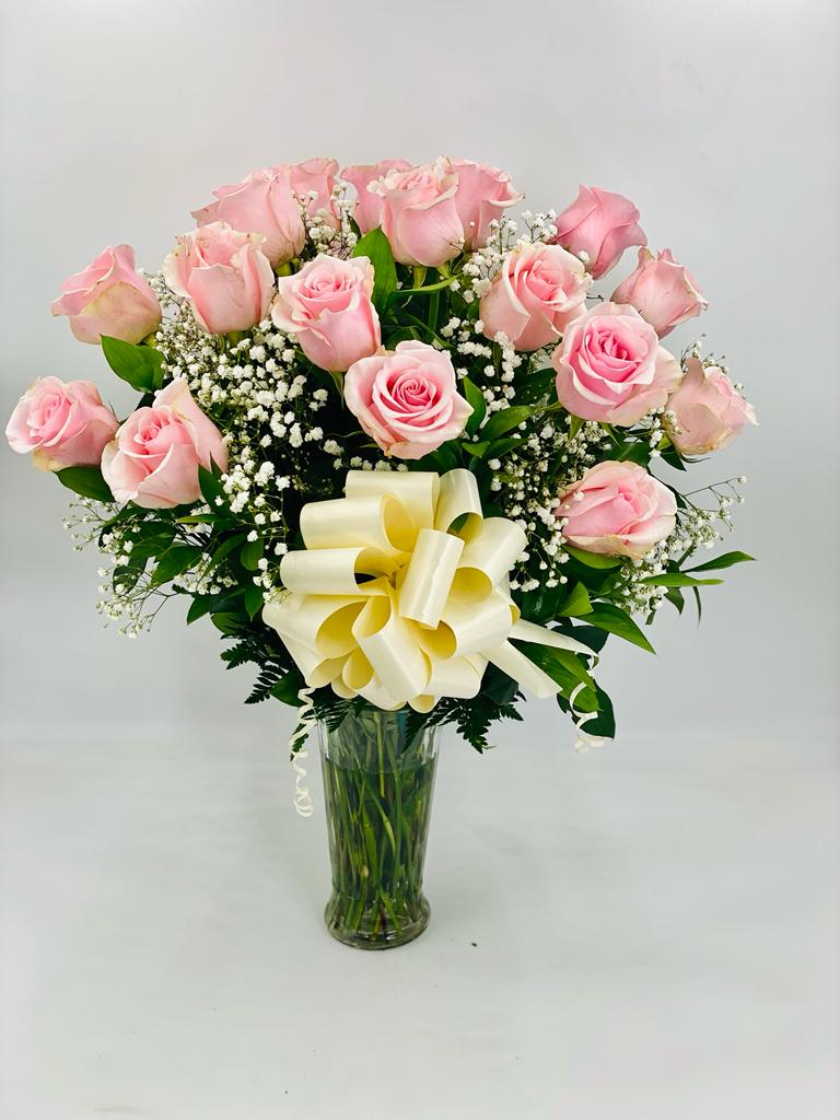 Pink rose bouquet in a clear glass vase with a cream ribbon bow